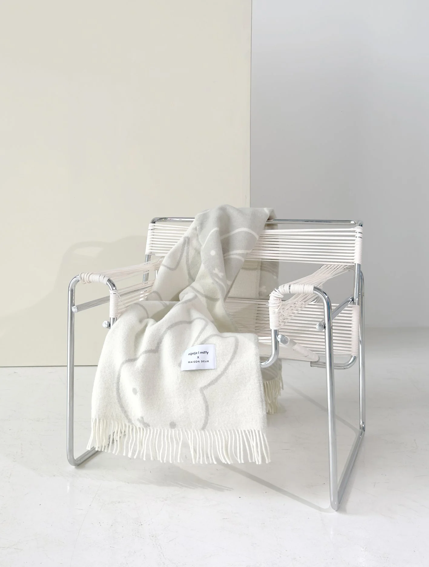 A blanket with Miff embroidered on over a chair with a white background