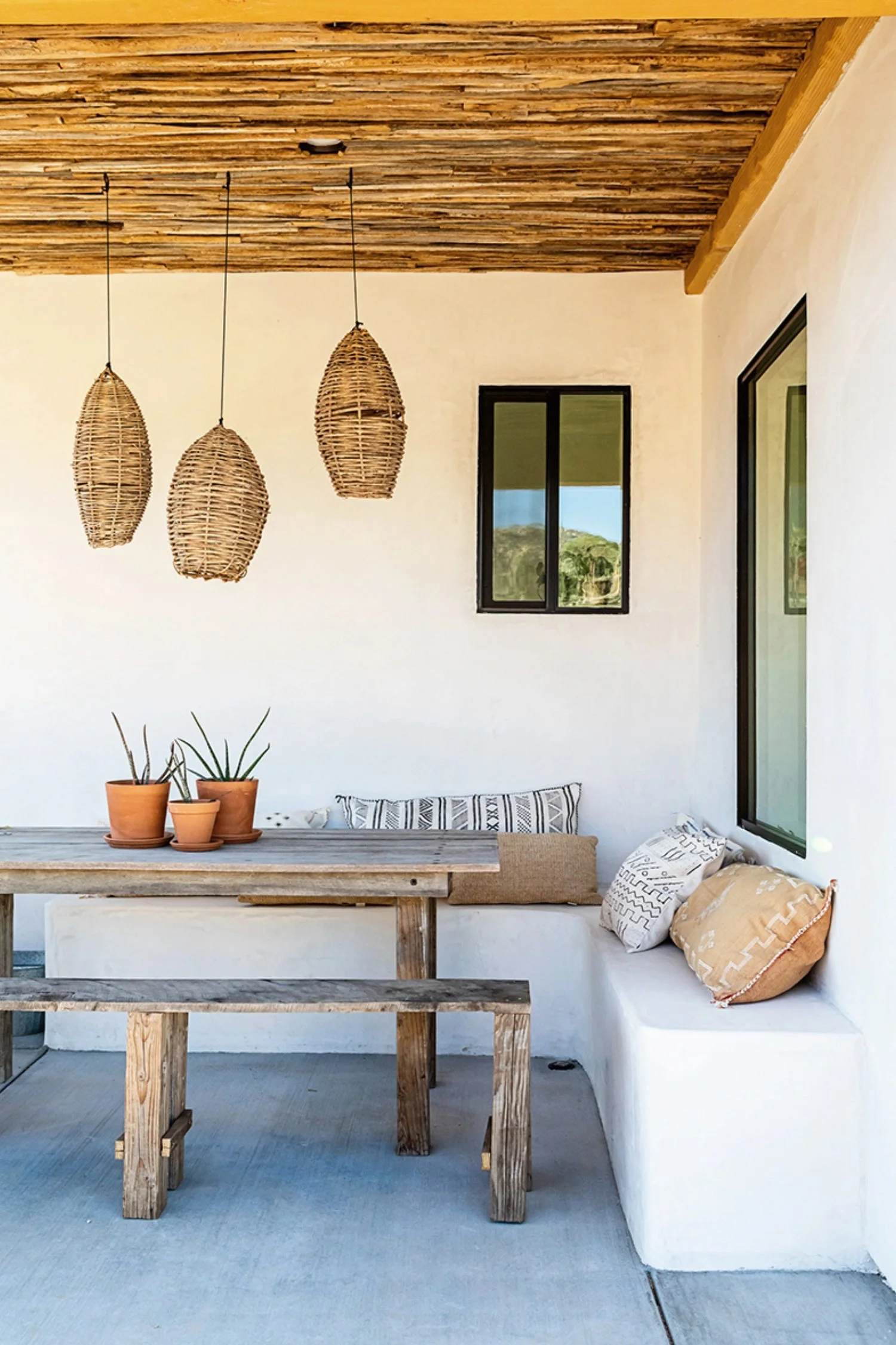 Natural woven outdoor pendant lights creating a stylish covered patio dining area.