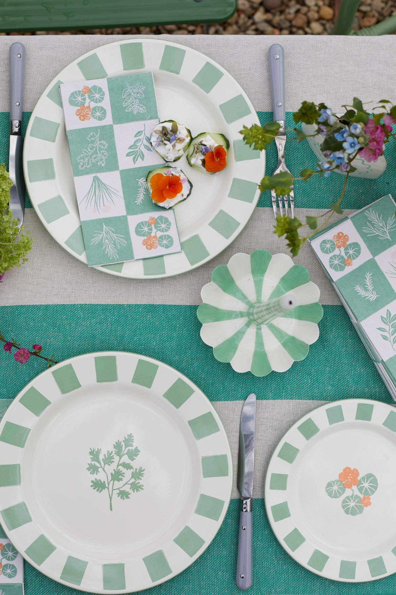 Botanical enamel plates with matching striped tablecloth, napkins and candle holders for outdoor dining.