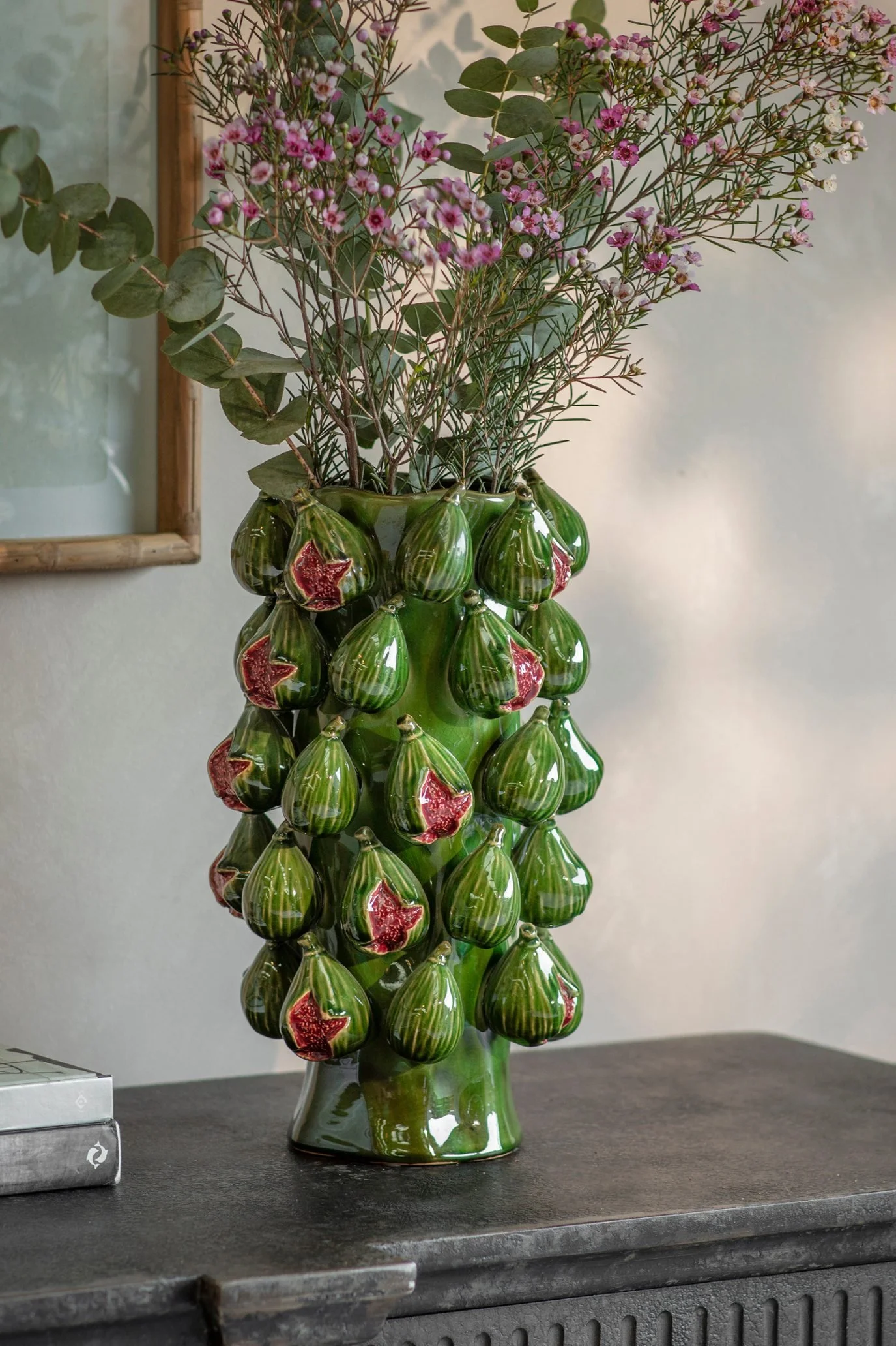 Green porcelain fig vase with textured pink figs and delicate flower stems.