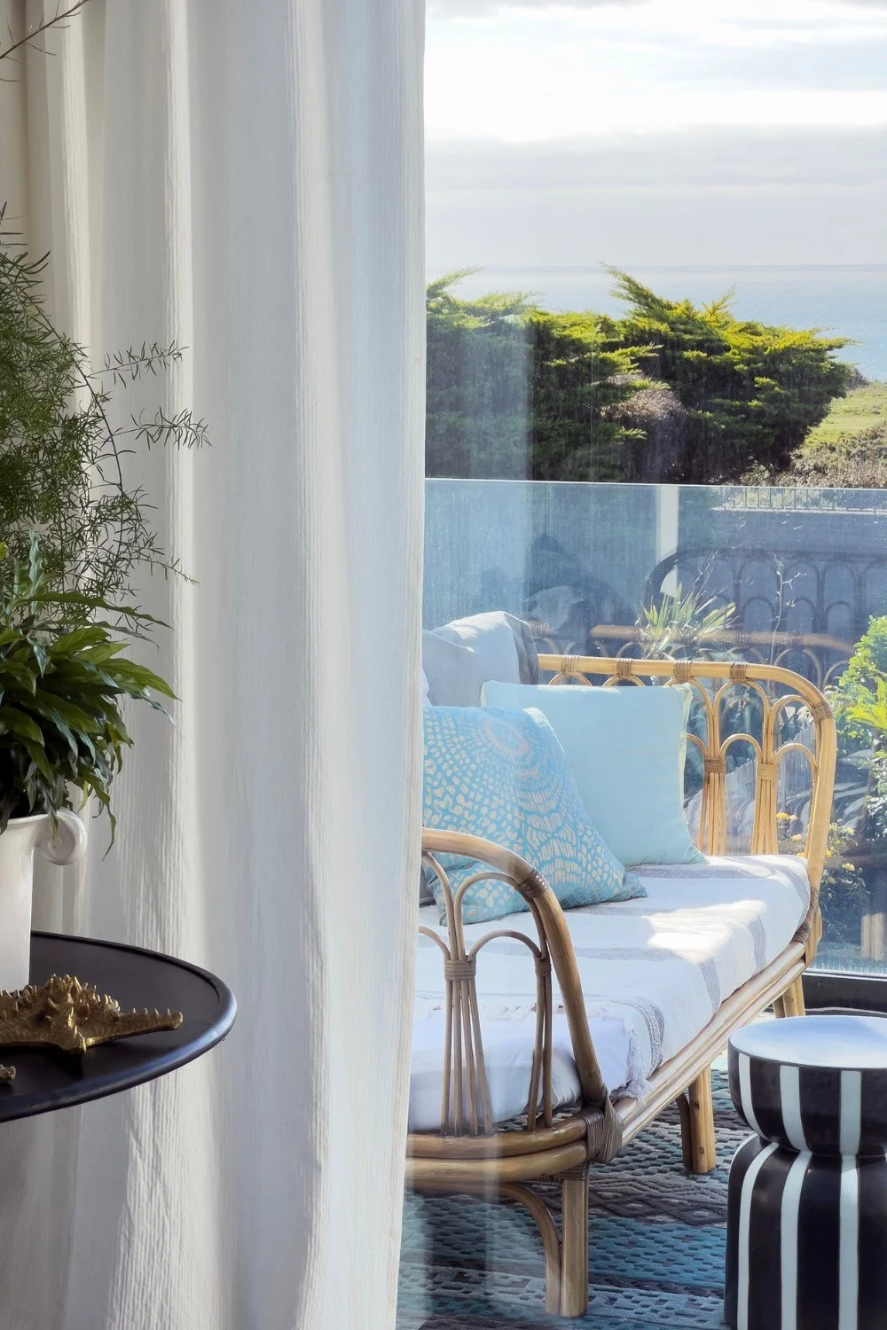 a balcony with a bamboo day bed with a mix of aqua cushions