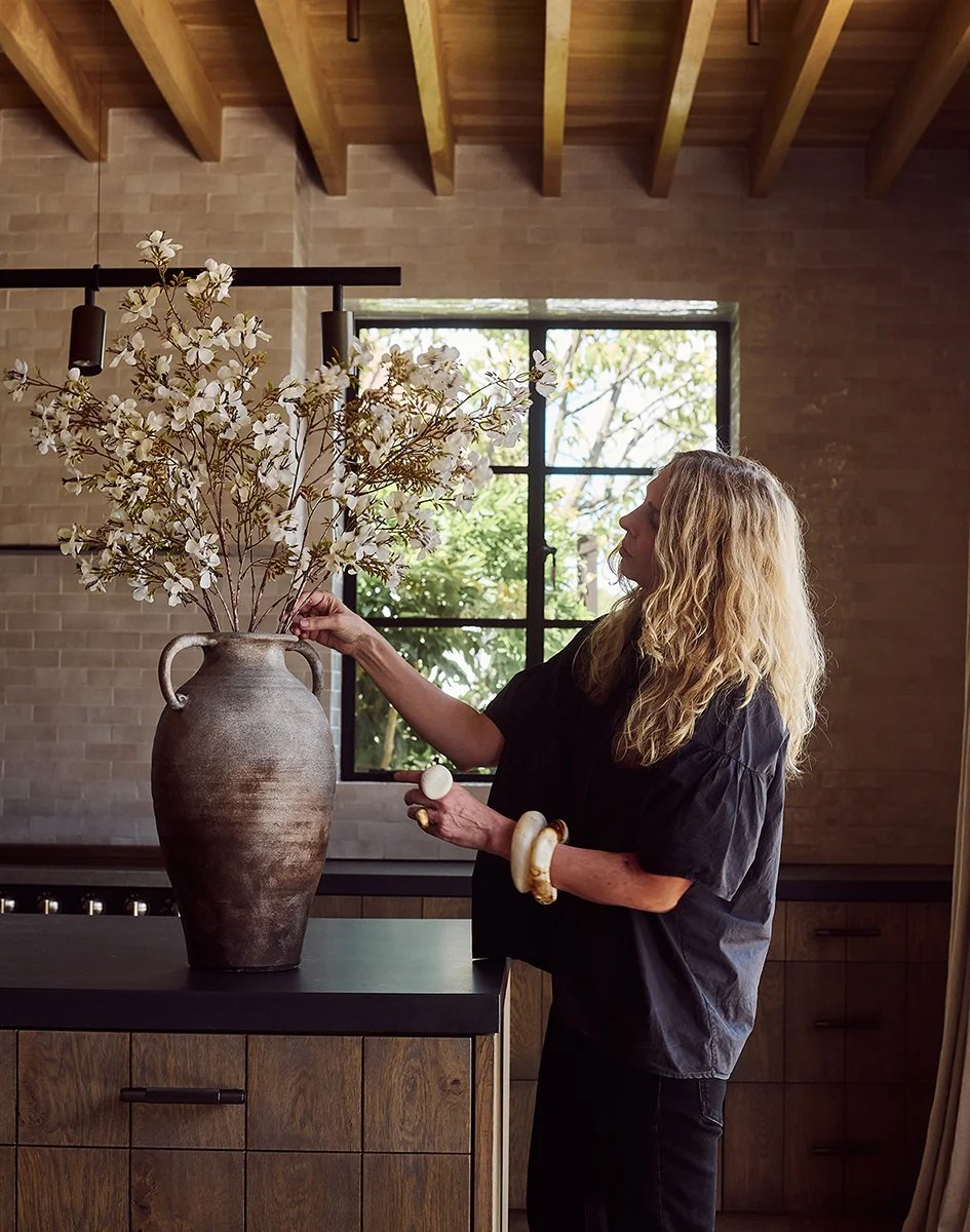 Interior designer arranging spring blossom in a tall terracotta vase