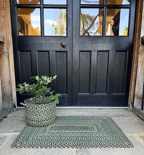 a double door with an aqua and blue embroidered rug and matching pot next to it