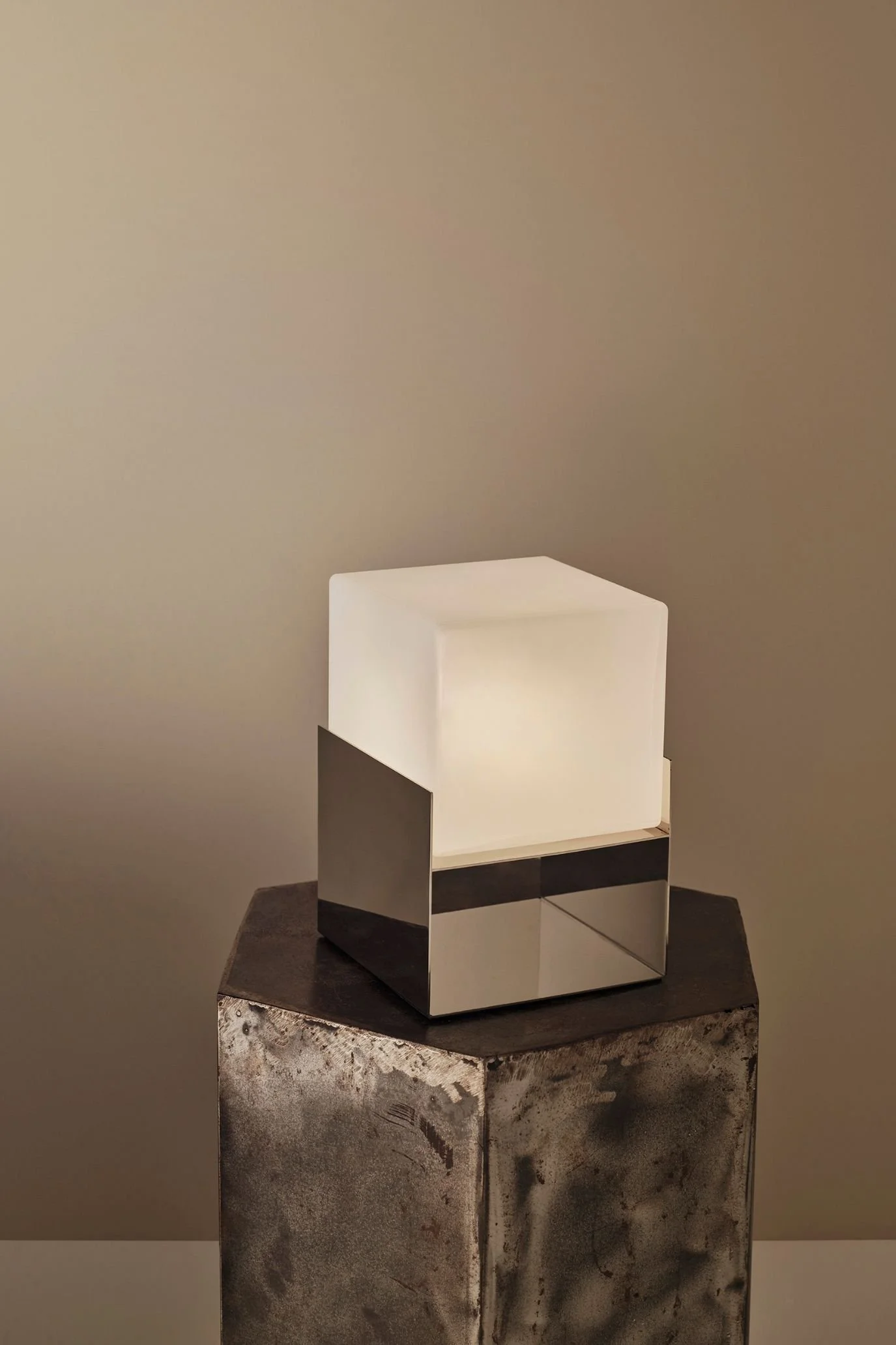 Kelly Hoppen x M&S square glass table lamp with a reflective metal base, styled on a textured pedestal.