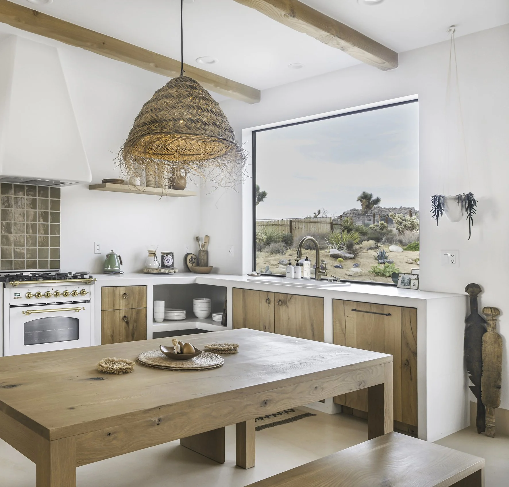 plaster countertops, wood cabinetry, and a large timber dining table handcrafted by local artisans. There is a woven pendant hanging above the table
