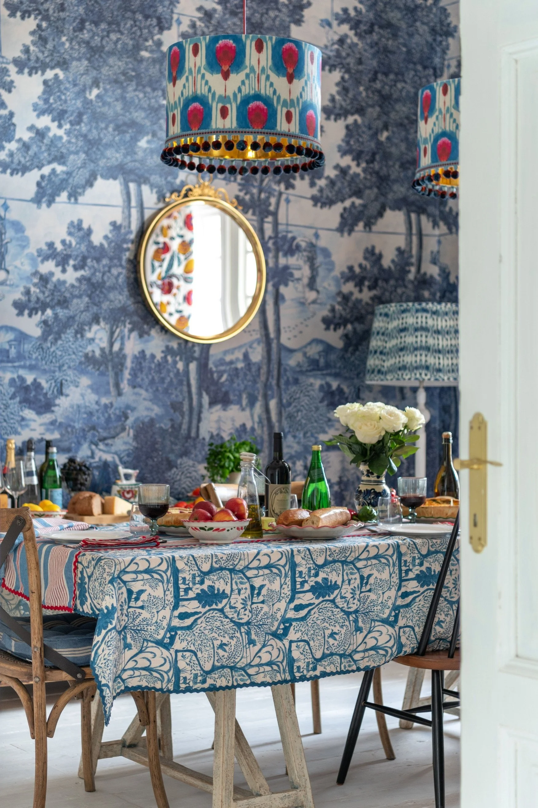 Blue tree wallpaper with a dining table in front with a blue printed tablecloth