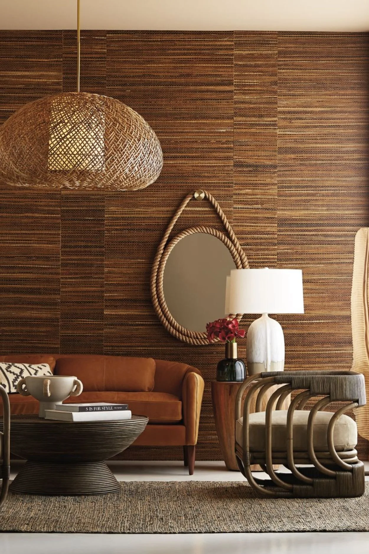a room with brown wallpaper a large rattan pendant and an oval rope mirror on the wall