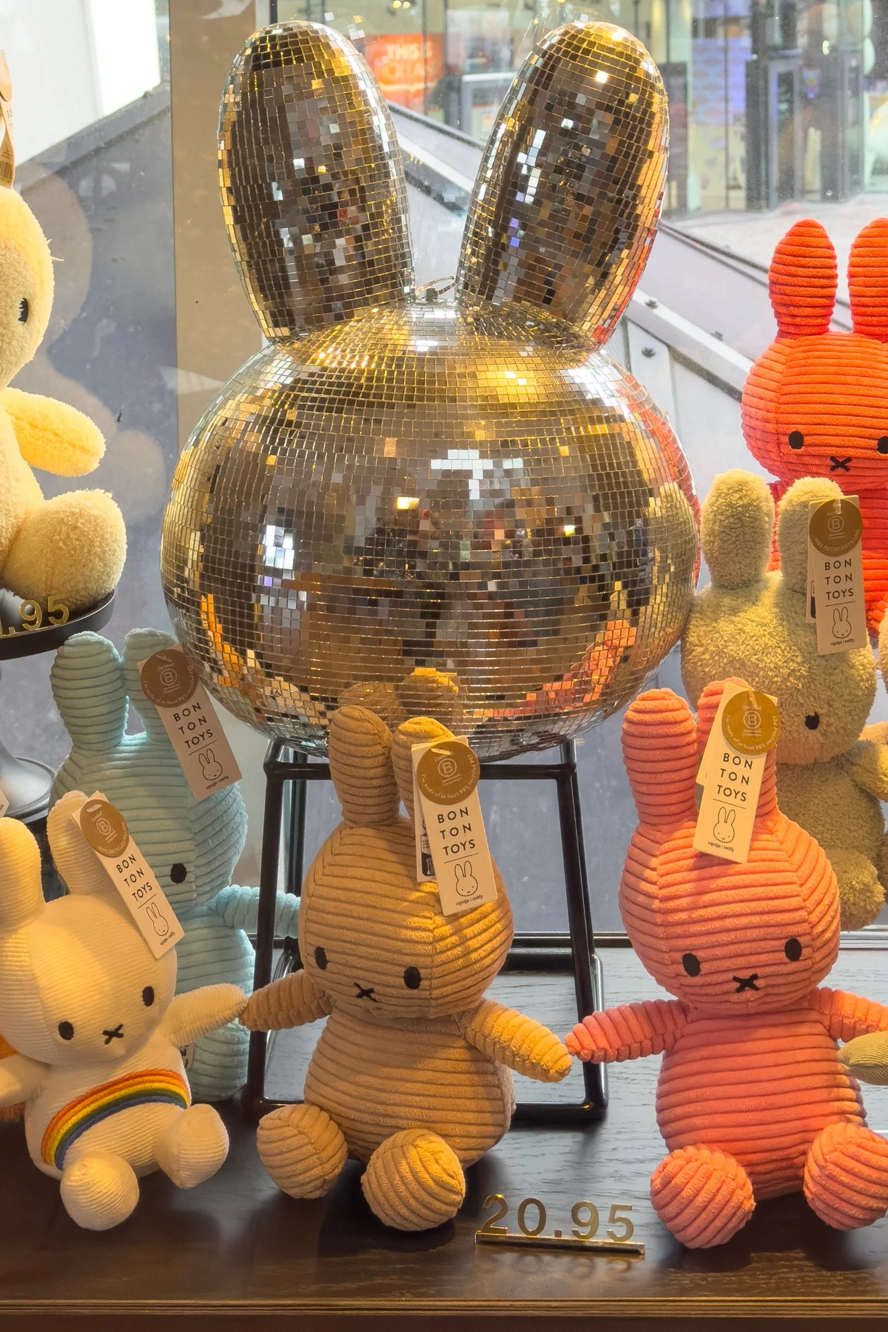 A disco head miffy surround by small miffy soft toys in yellow and orange