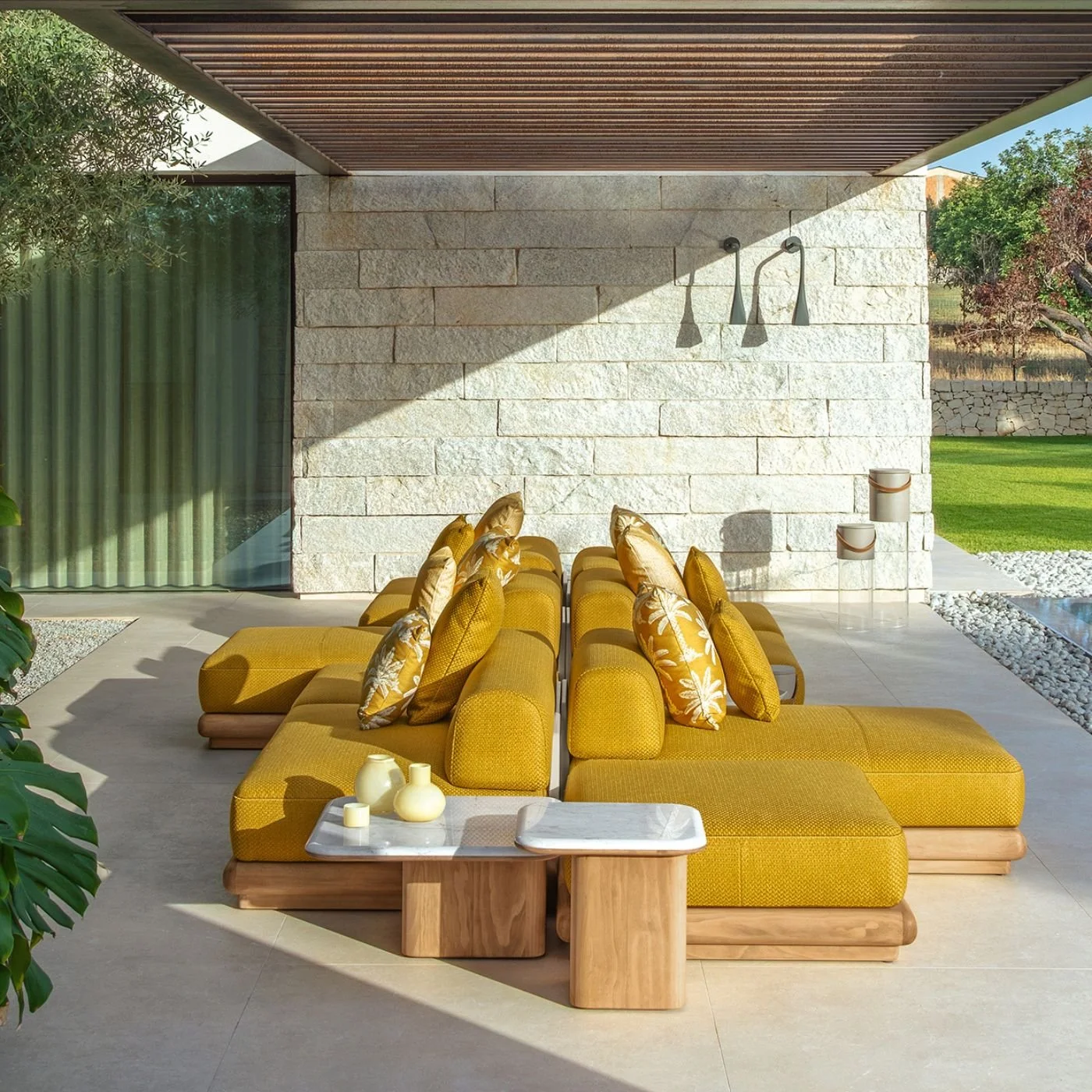 A yellow designer sofa with accent cushions in yellow and white  with a set of two outdoor side tables