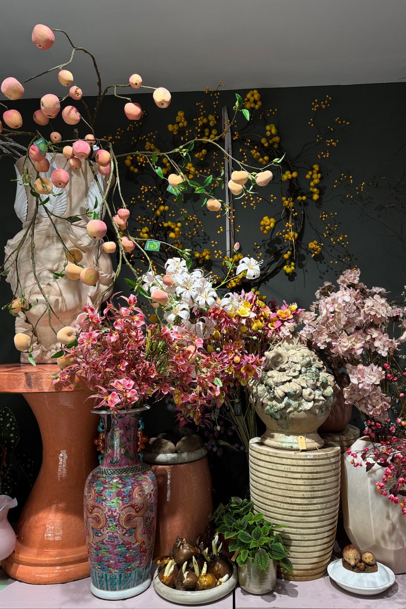 Colourful faux flowers and flowering branches displayed in decorative vases in a flower shop.
