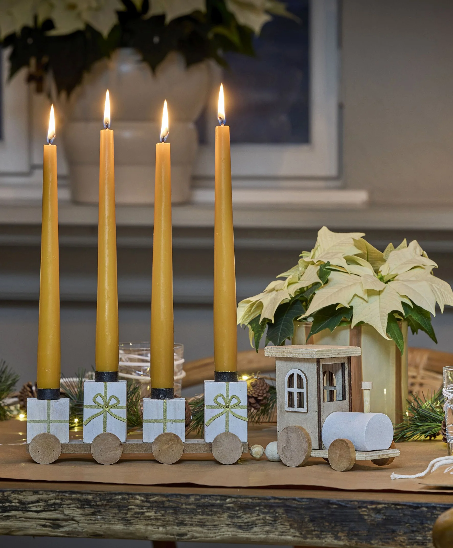 A train candle holder with four carriages all holding a gold candle each