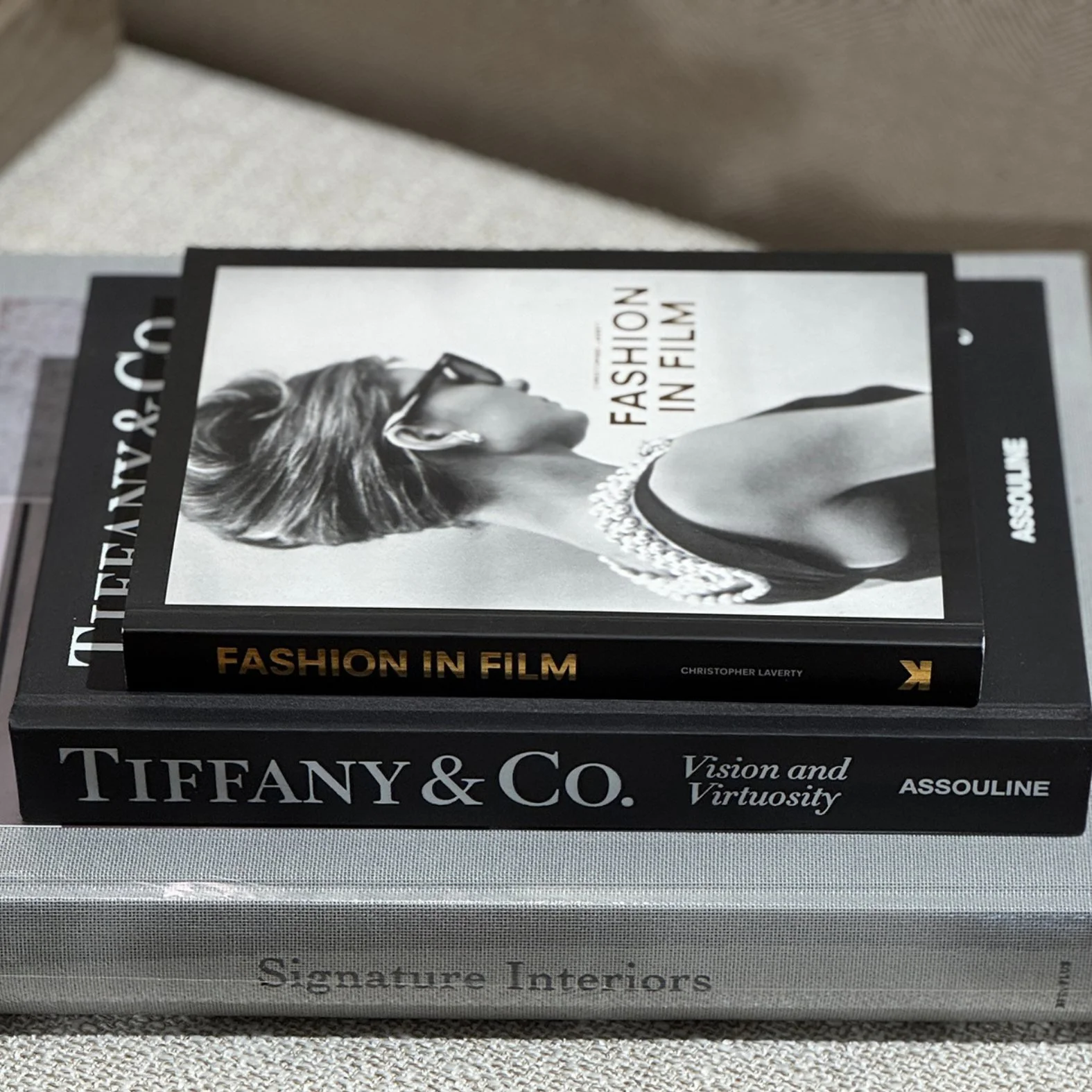 stylish books about interiors, Tiffany & co and Fashion in film placed in a pile on a wool ottoman.