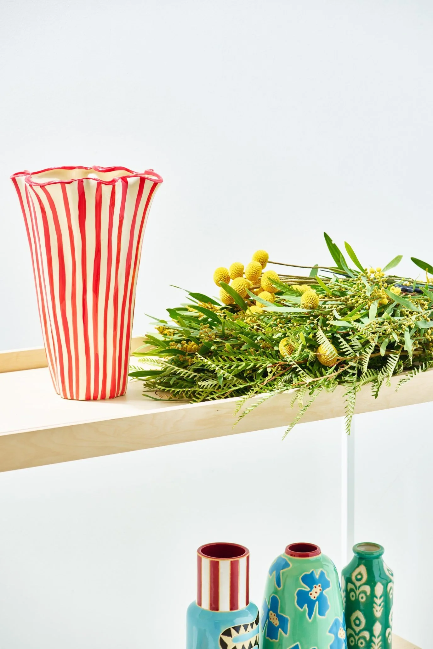 Tall red and white striped ceramic vase with an asymmetric wavy red rim.
