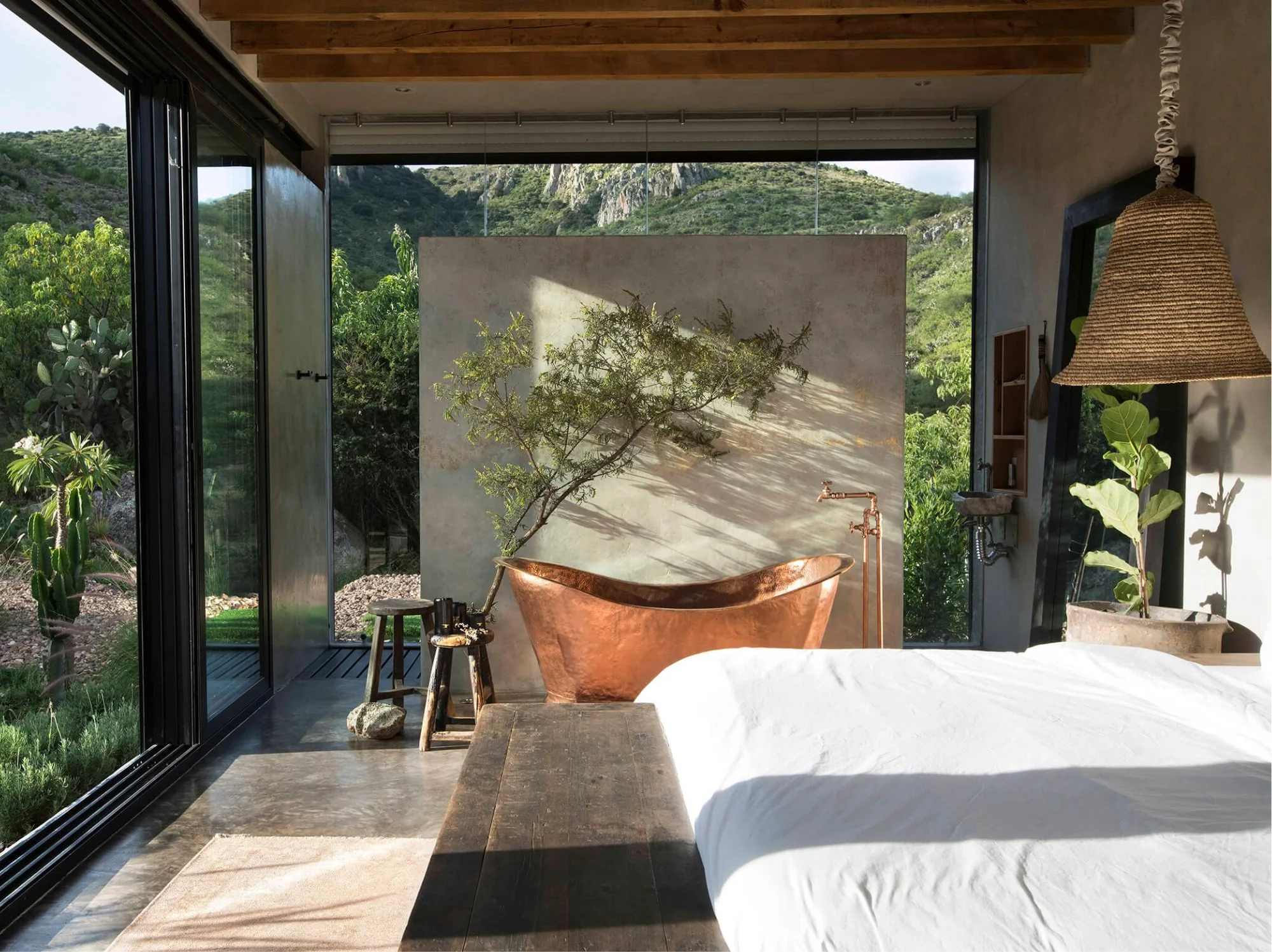 Mirrored luxury vacation rental in the Mexican desert with a sculptural outdoor bath overlooking dramatic mountain scenery.