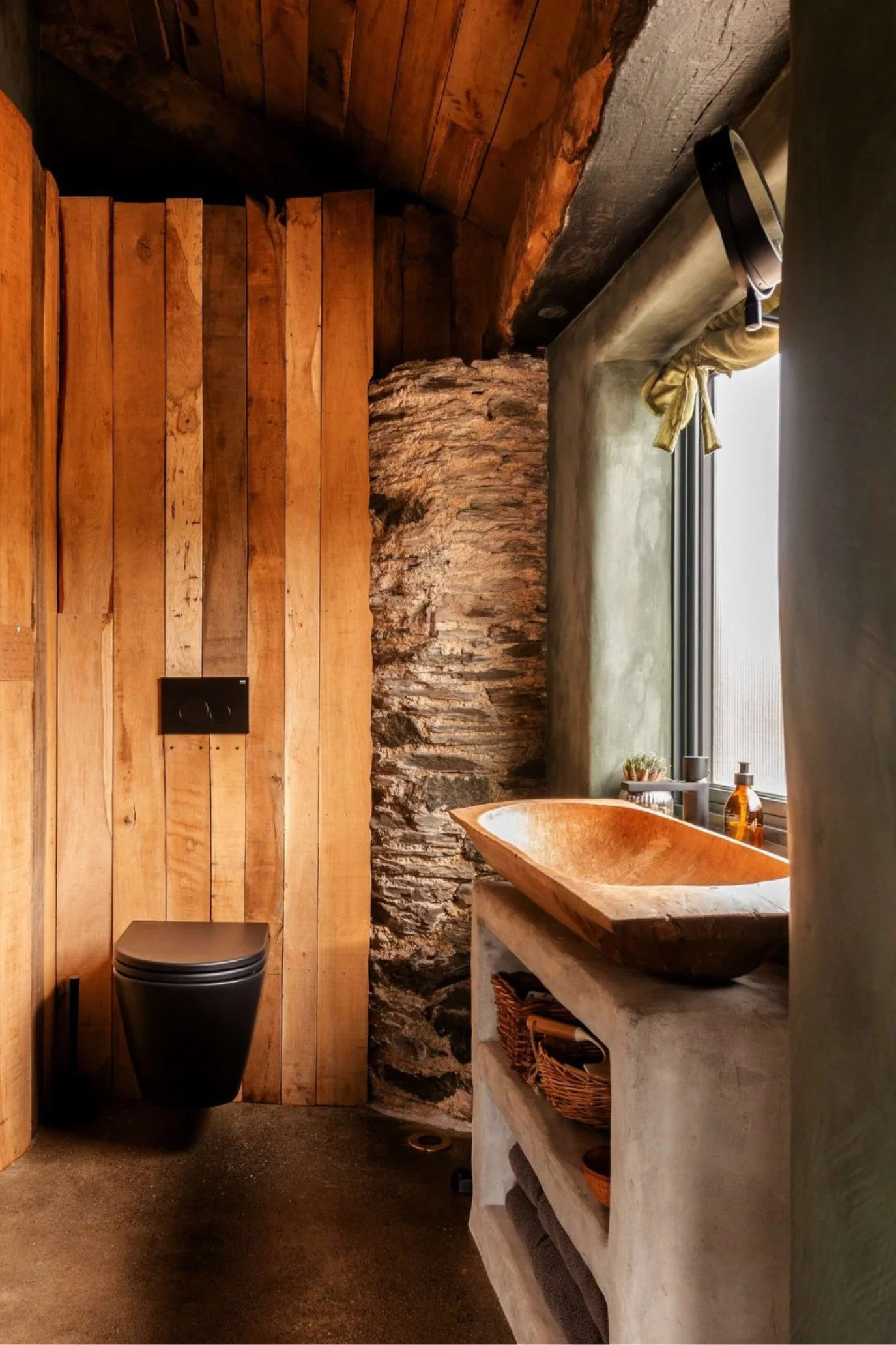 The bathroom in a Devon barn conversion full of original stone and a wooden trough used as a basin