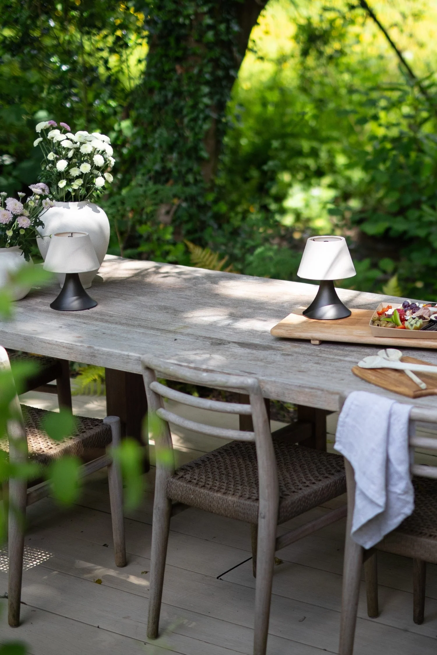 Outdoor lighting ideas featuring rechargeable portable table lamps styling a contemporary garden dining table.
