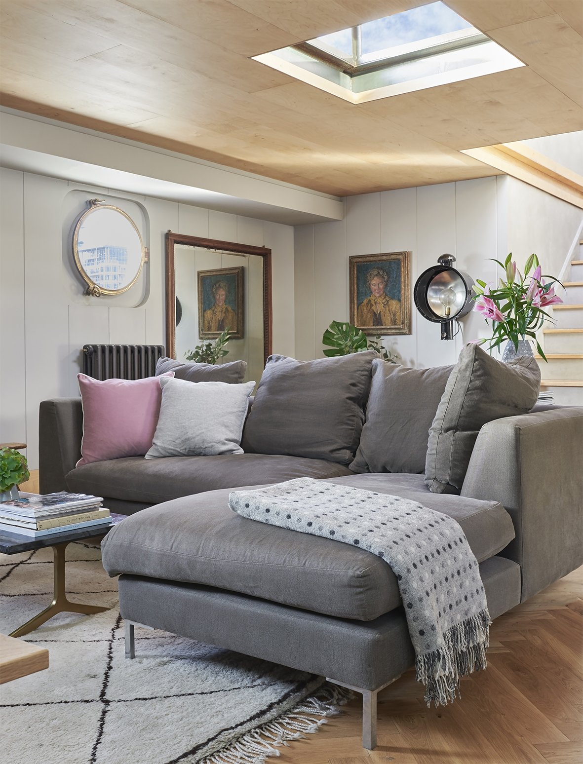 Stylish home decor a wooden throw in a poka dot design  on a grey sofa in the living room of a house boat.