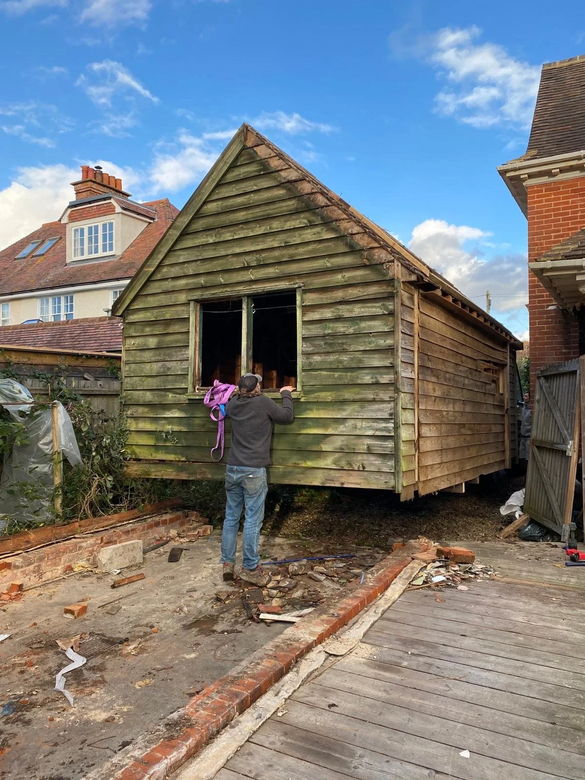An old wooden garage being removed with a man standing at the window