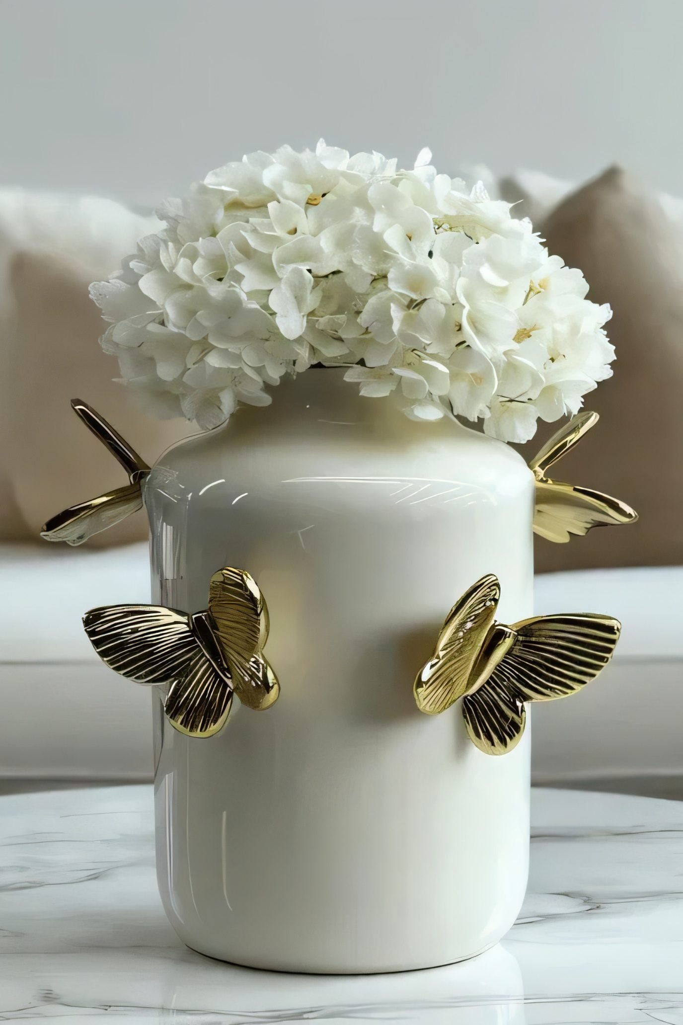 Cream glazed ceramic vase with raised gold butterflies and white hydrangeas.