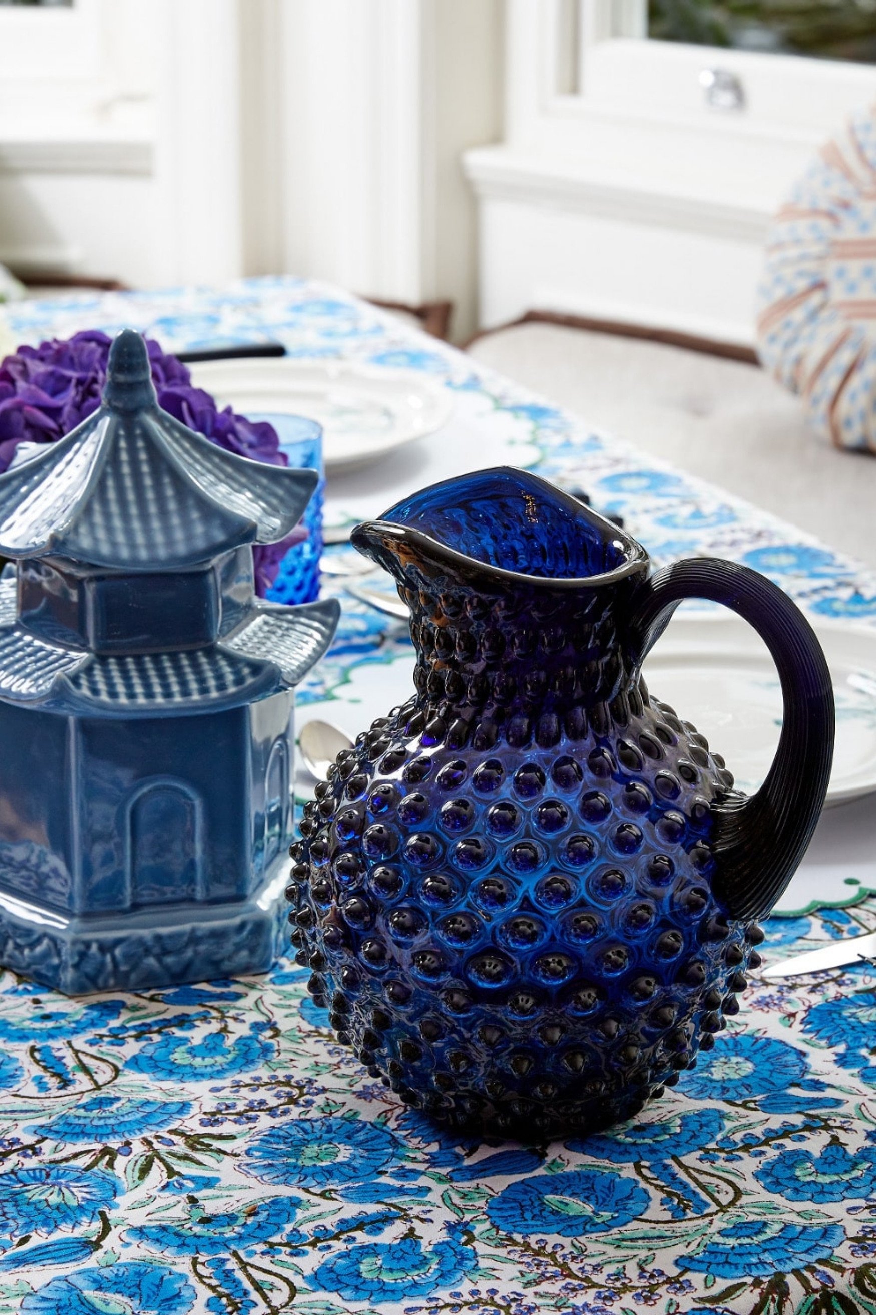 A blue jug on a blue and white floral table cloth