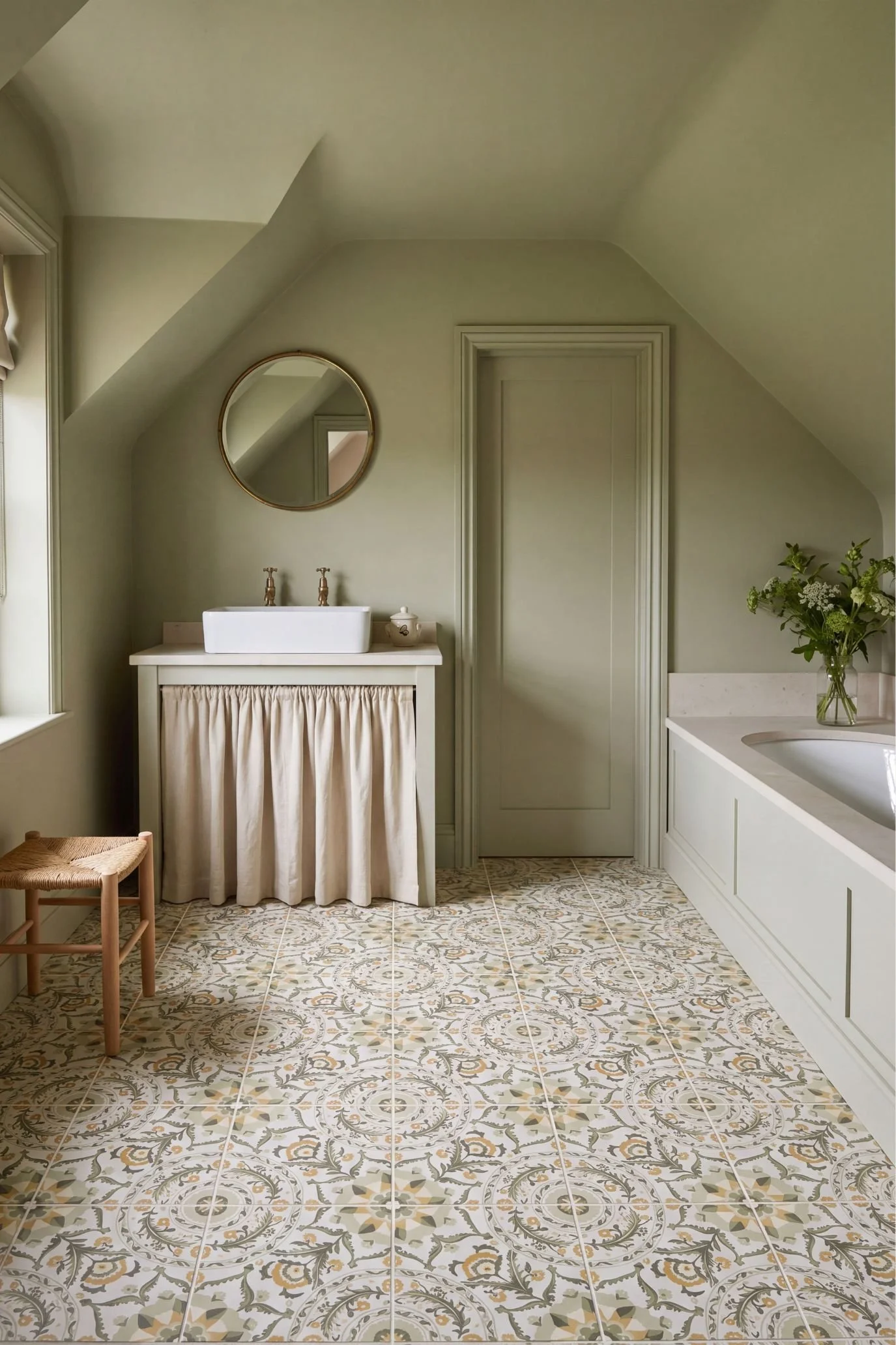 bathroom painted in soft green with a patterned tiled floor