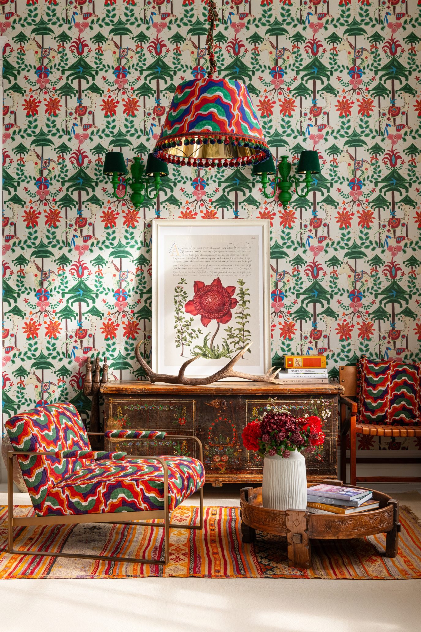 a room with wall paper in a repeat flower pattern with a framed picture and light on the wall and a chair