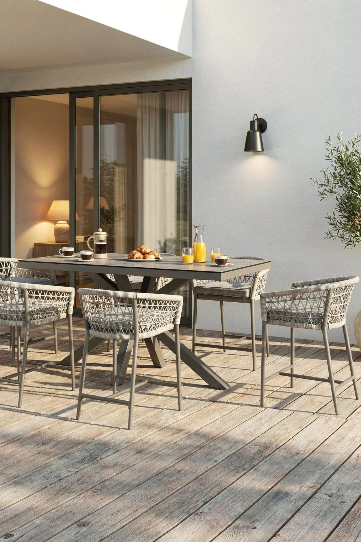 Outdoor bar-height dining table and woven bar stools styled for breakfast on a contemporary terrace.