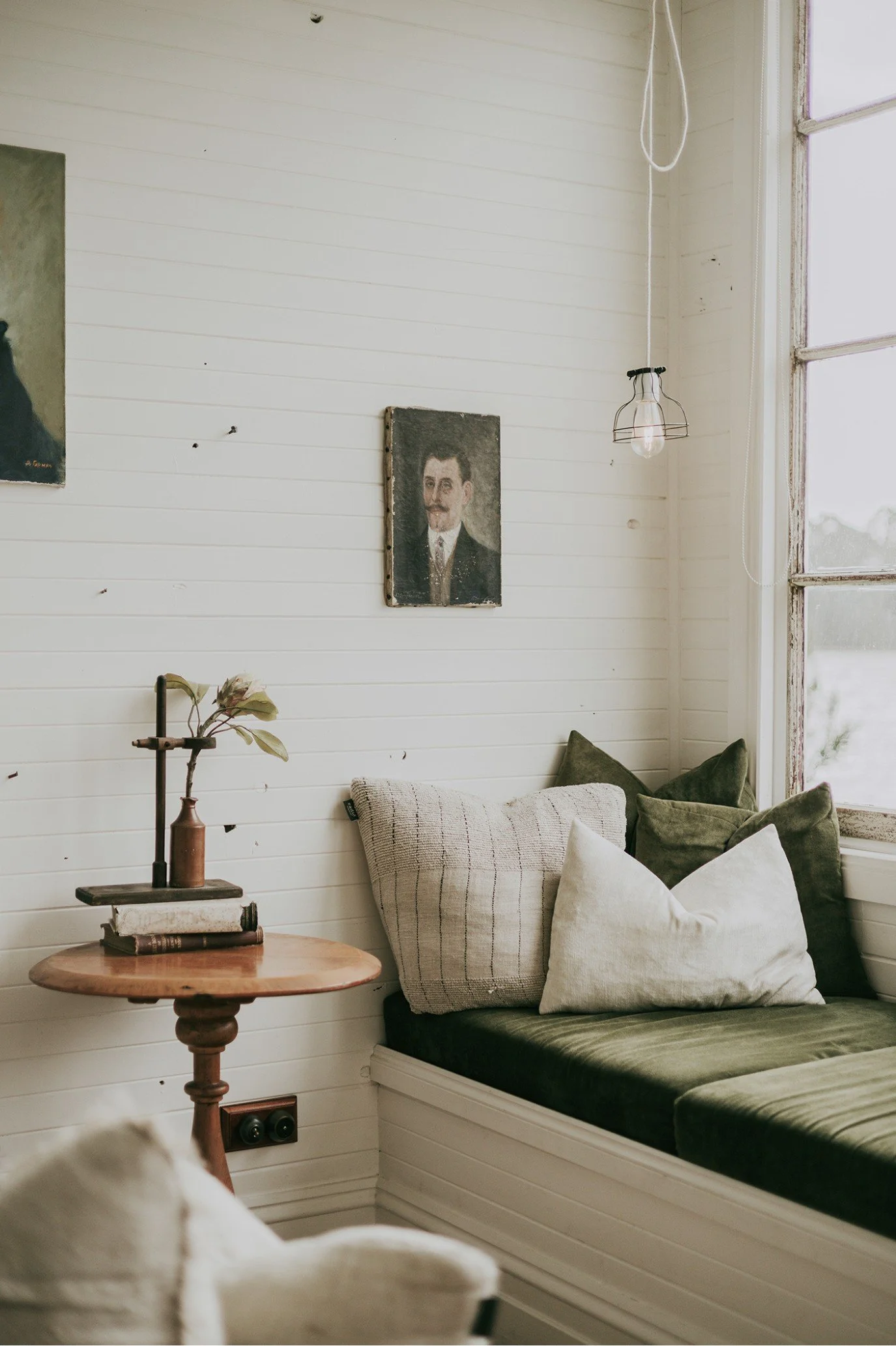 Vintage day bed at Captain’s Rest layered with green velvet cushions, textured linens and antique artwork.