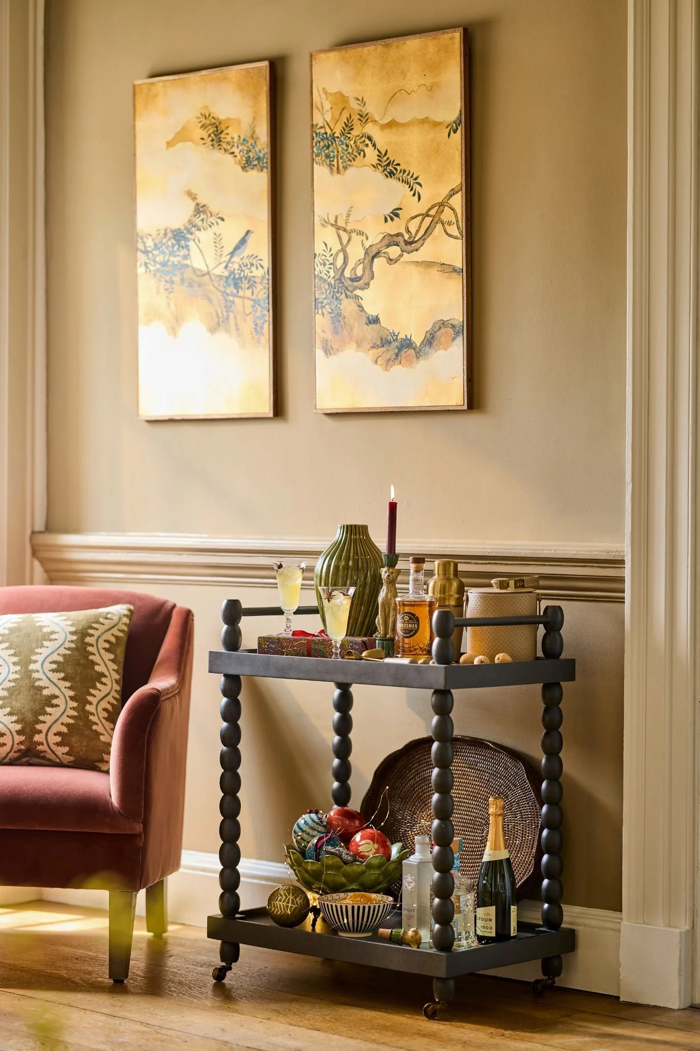 Bobbie style legged Black bar cart with bottles and cocktail glasswareBlack bar cart with bottles and cocktail glassware bar cart in front of two picture panels