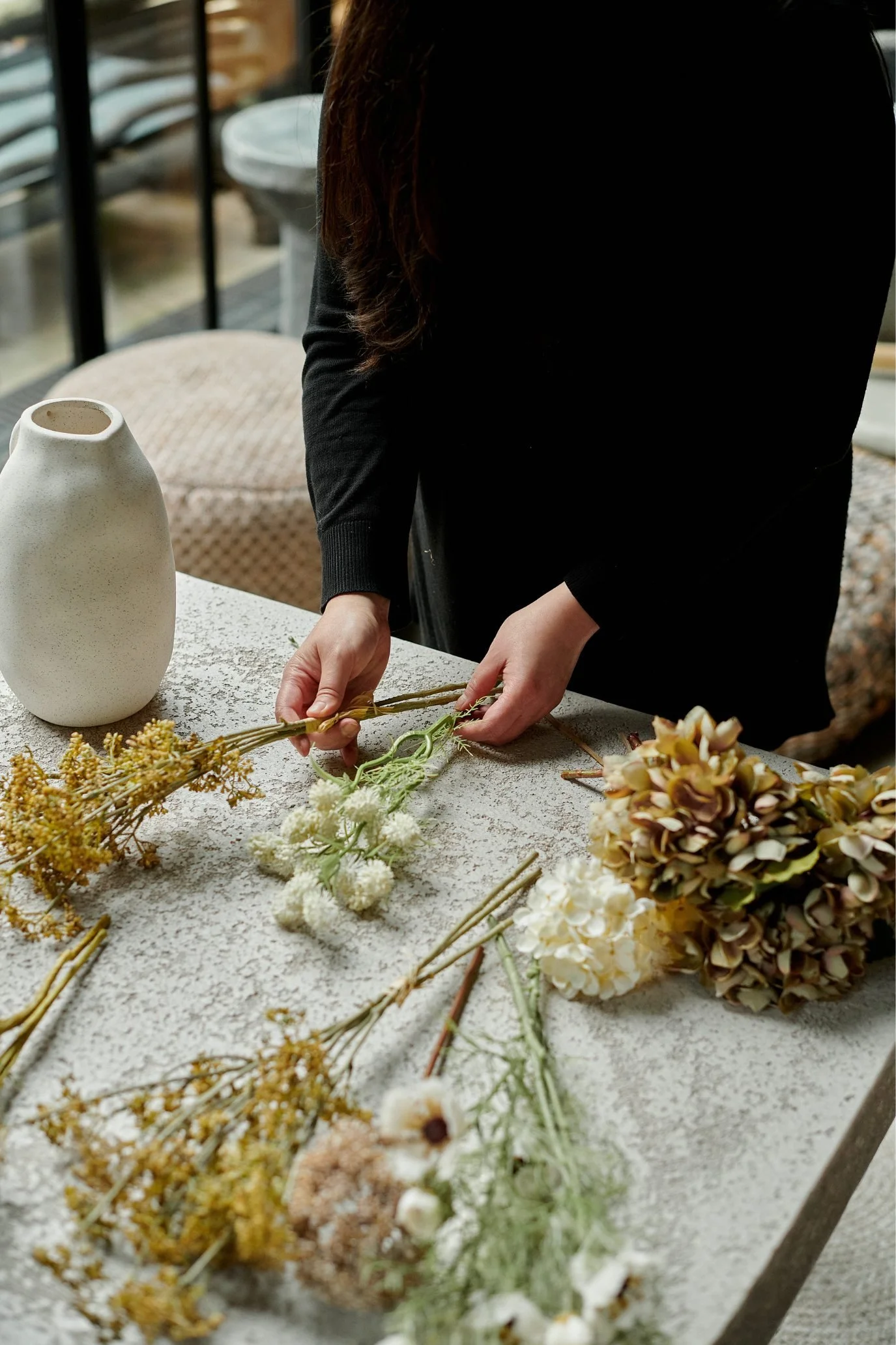 Faux flowers and stems laid out on a table ready to be arranged in a vase.