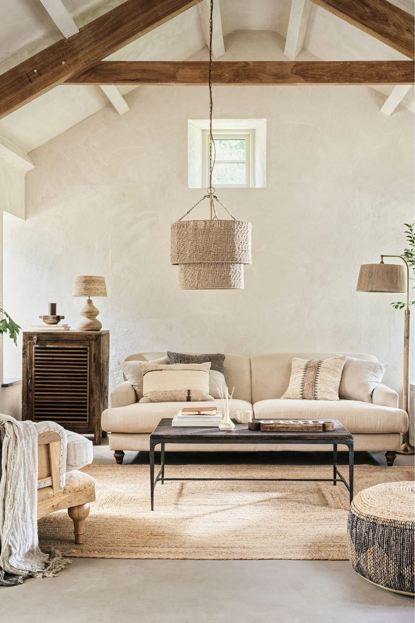 A living room in place tones with a beige linen sofa and rattan  lamp shades and pendant light