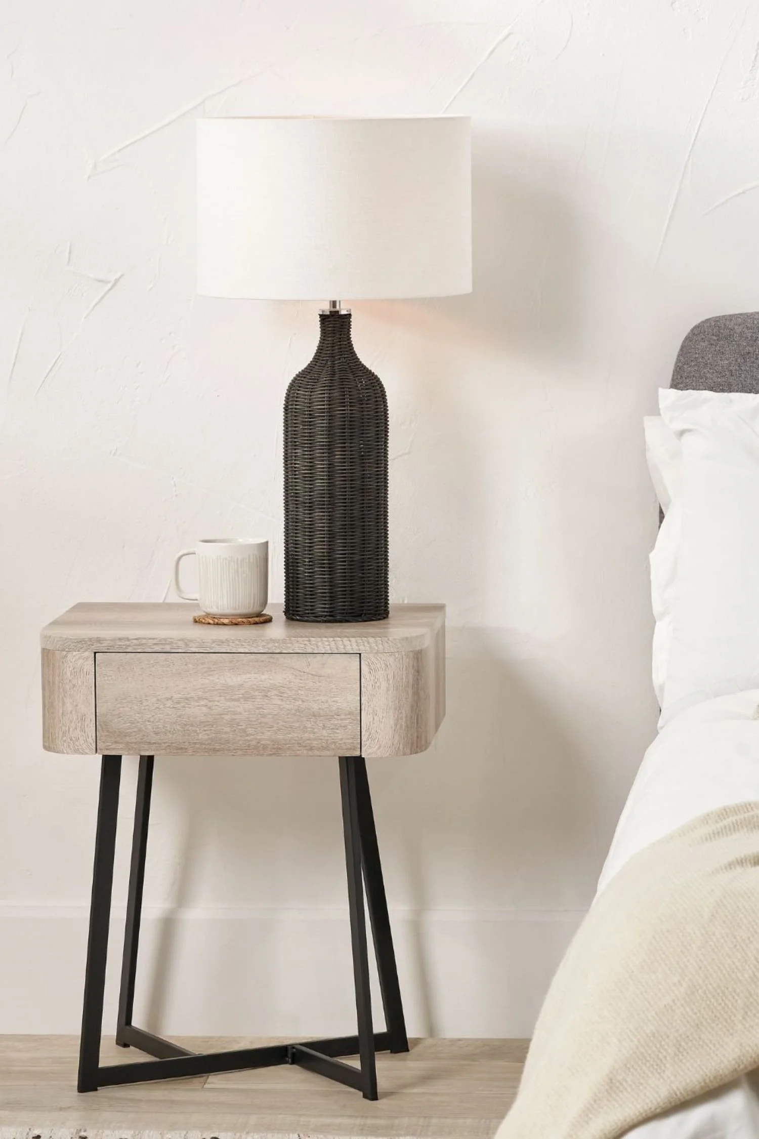 Scandinavian-inspired light grey oak nightstand with slim black metal frame and woven lamp