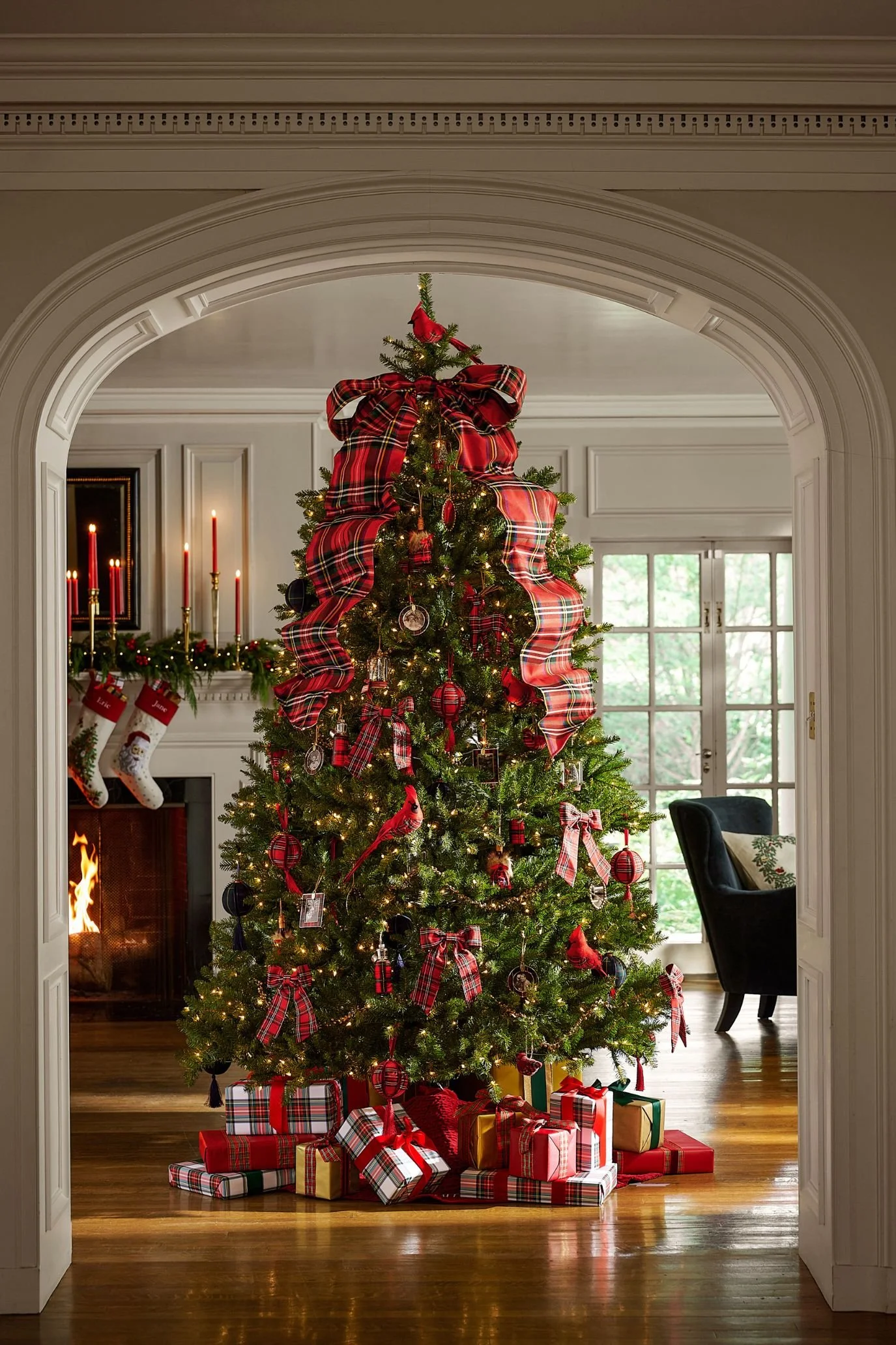 Christmas tree with an oversized red tartan bow, cascading ribbon and red and gold ornaments, surrounded by coordinating presents.