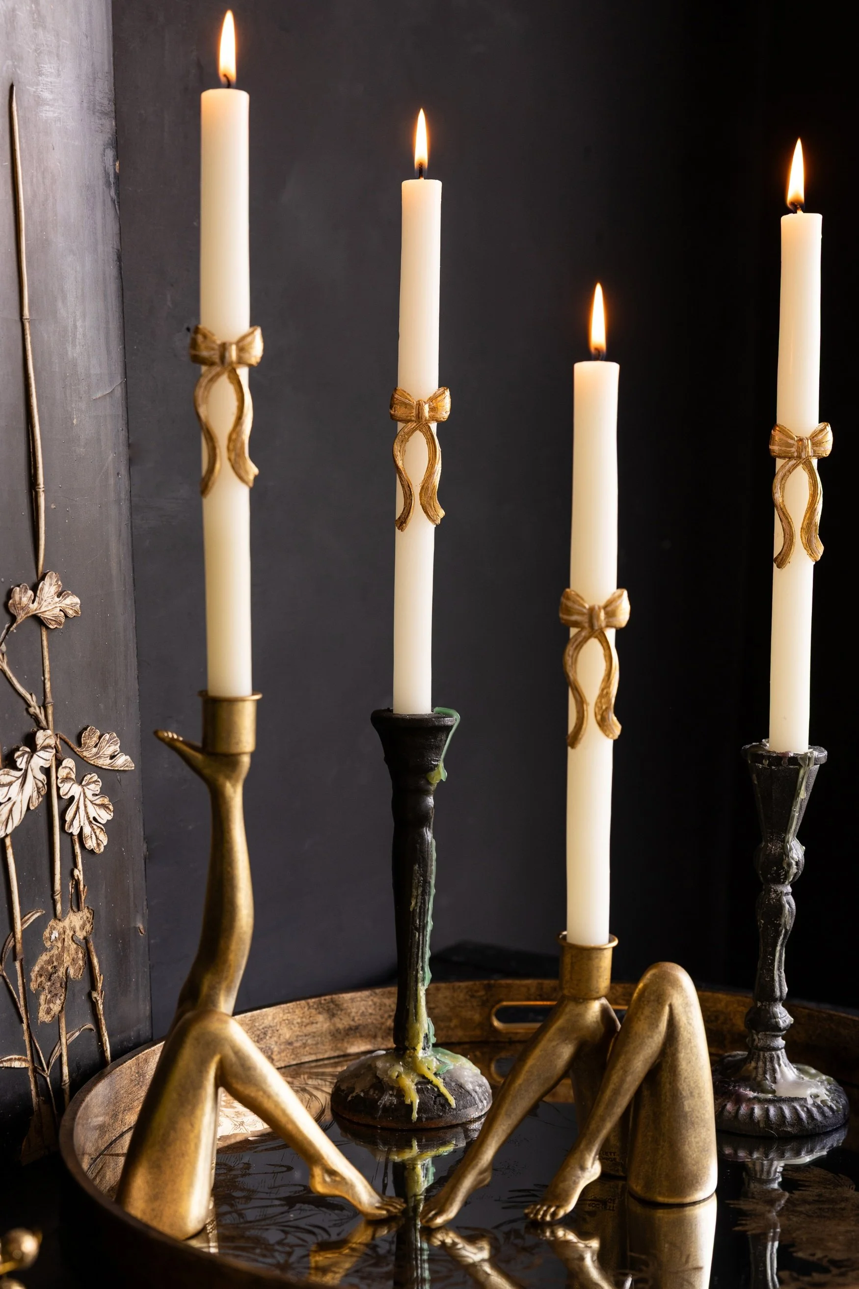 Four candle holders all with candles with gold bows