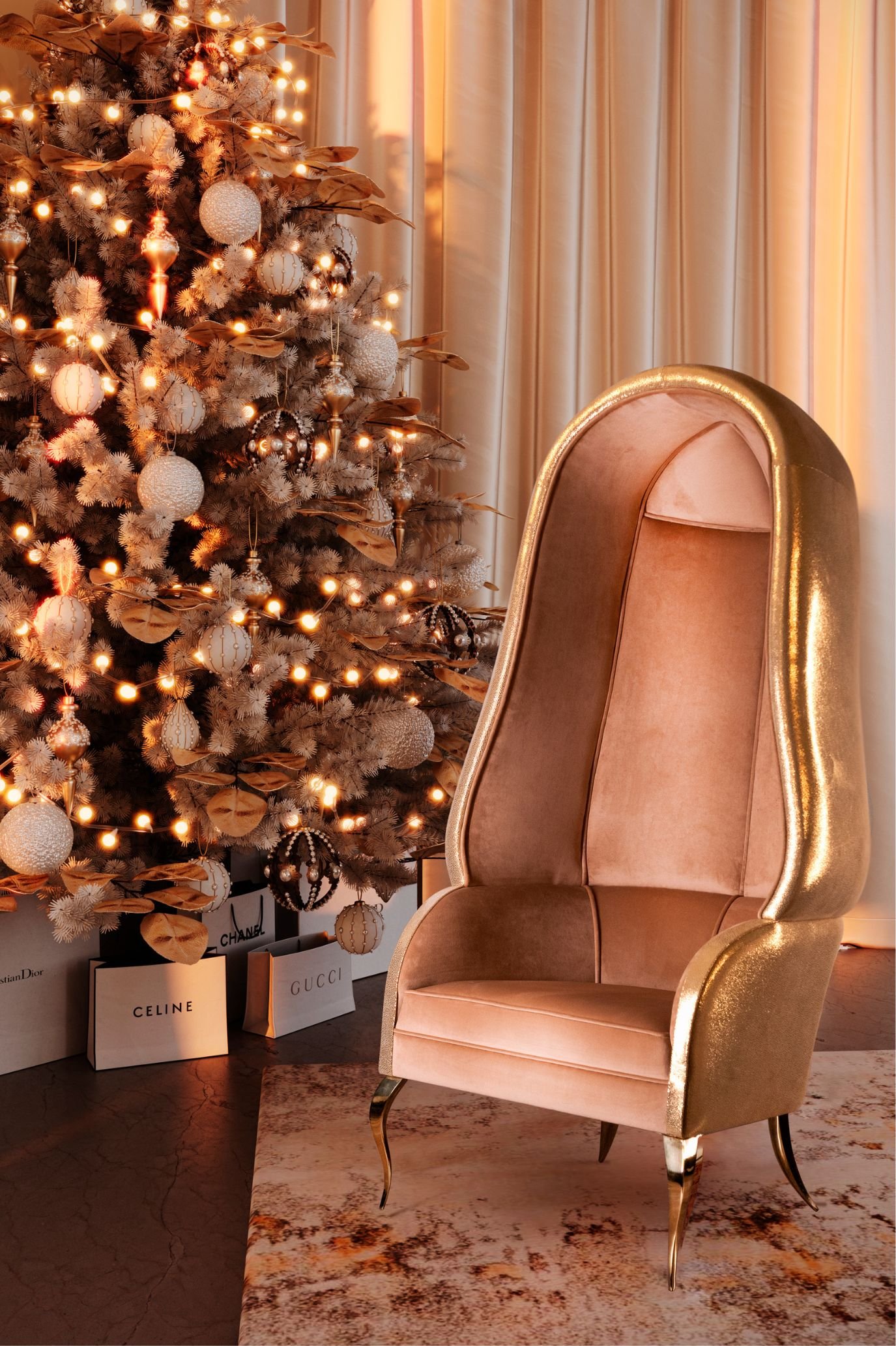 Christmas tree with peach, blush and champagne decorations and warm lights beside a peach chair with a gold frame.