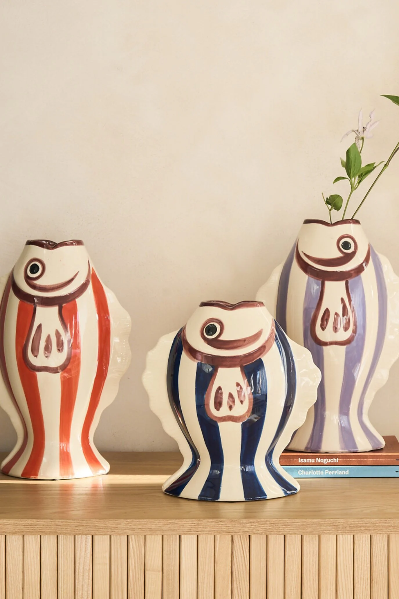 Three colourful striped fish-shaped vases grouped together at different heights.