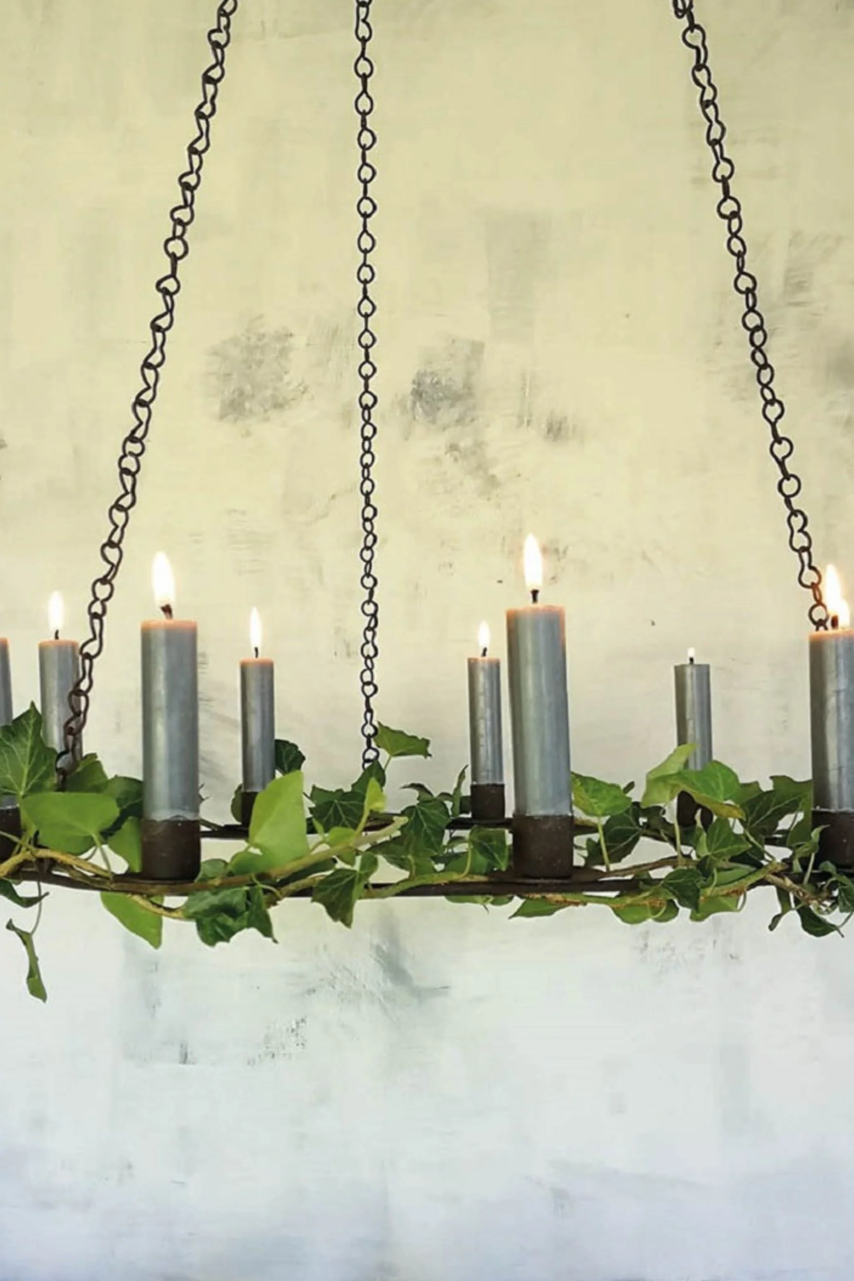 A hanging chandelier on chairs with candles and ivy around it