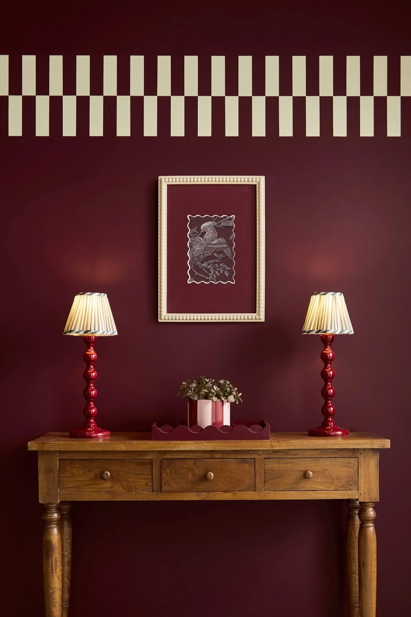 Entryway painted in Graham & Brown Divine Damson with red lamps, artwork and warm neutral accessories.