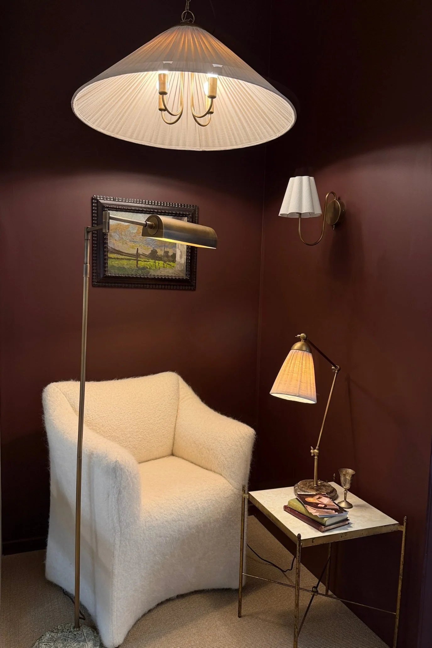 Merlot-toned wall with off-white bouclé chair, marble table and metallic lighting displayed at Design Week.
