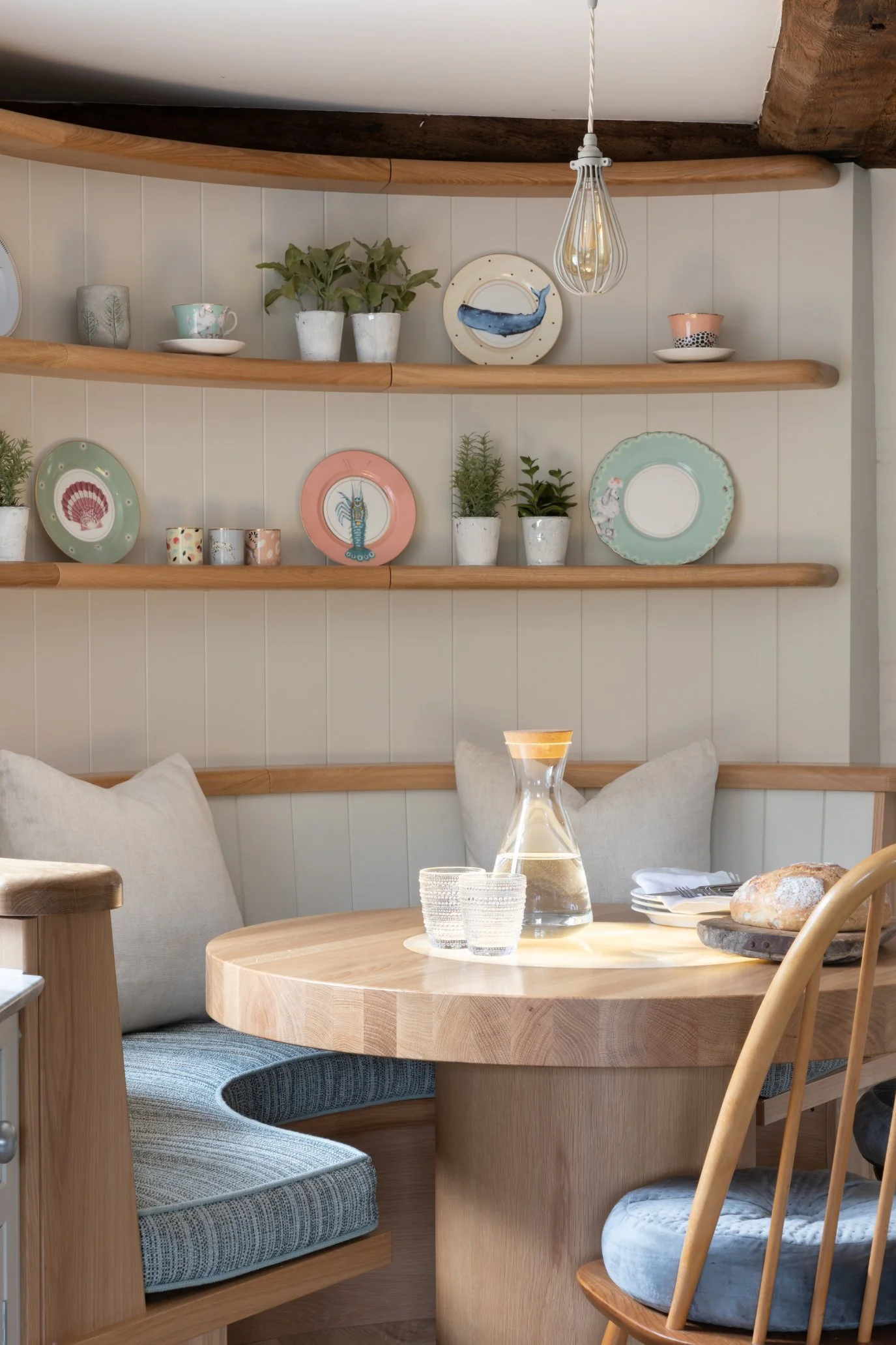 A curved dining area with curved wooden shelves displaying plates with a coastal theme
