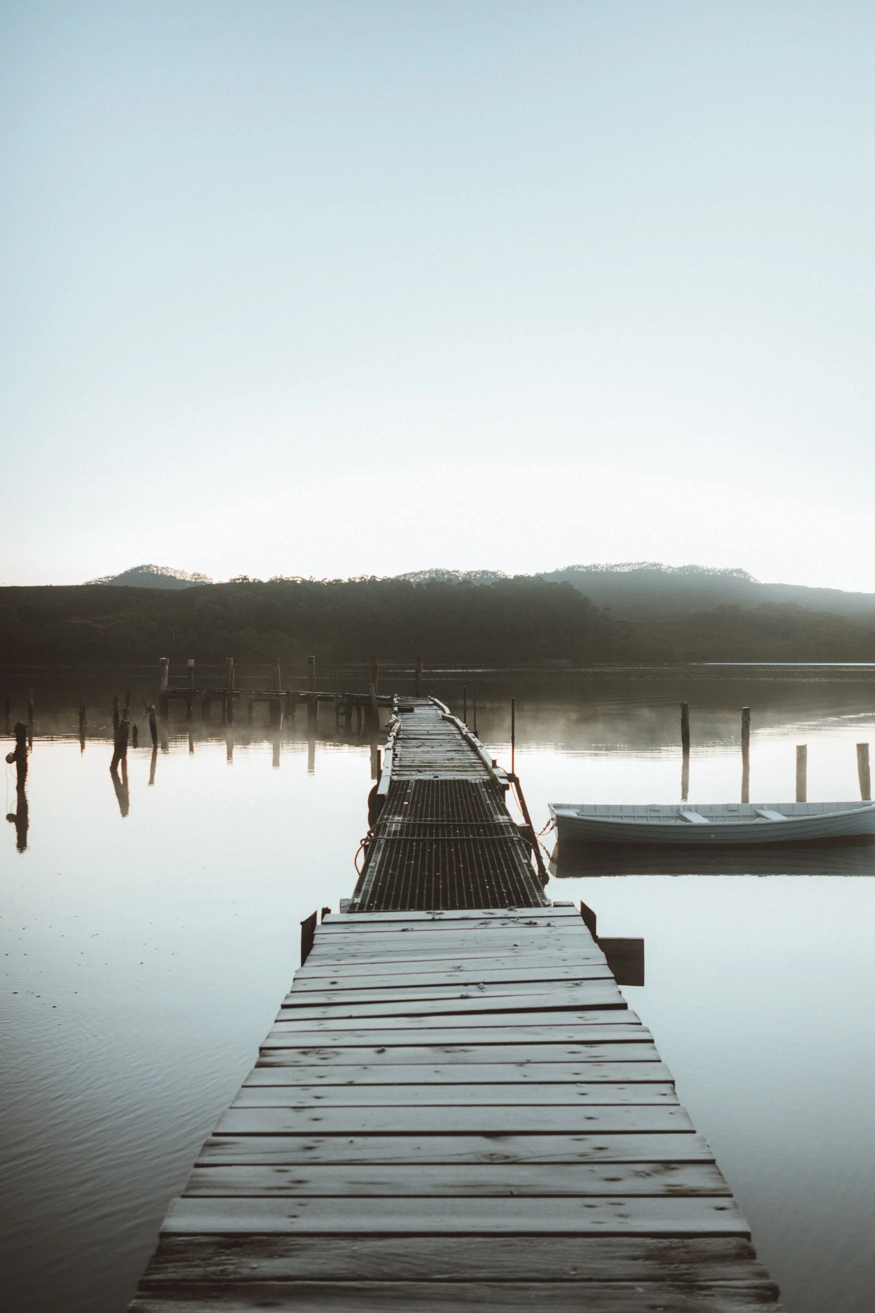 A wooden jetty with a small rowing boat on an estuary