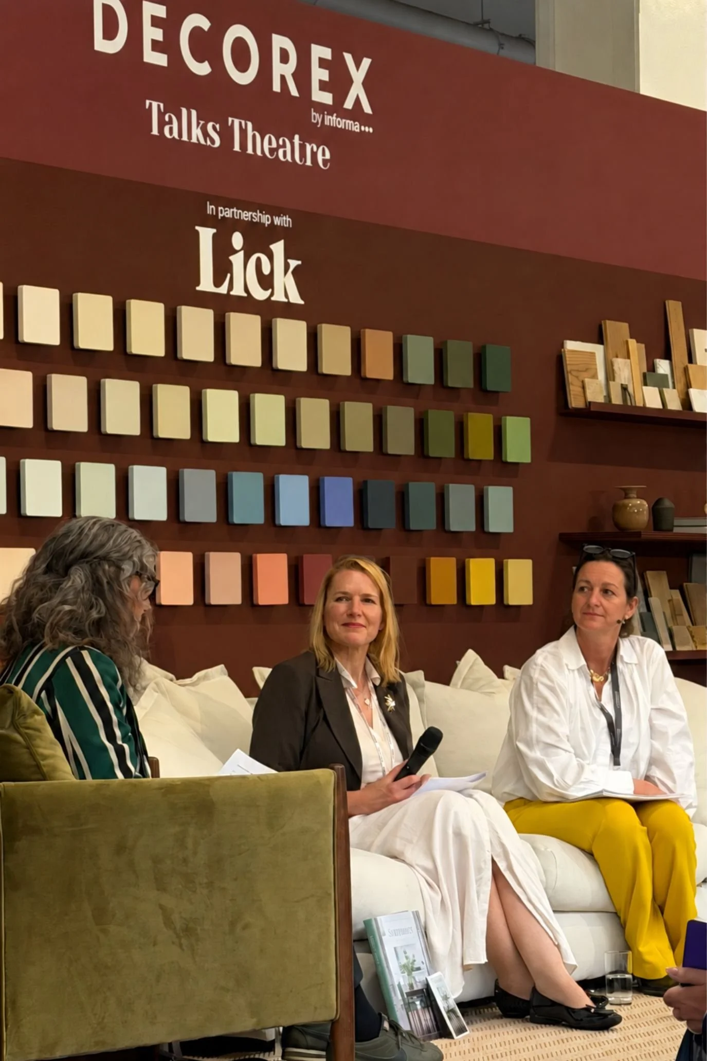 Panel discussion in the Decorex Talks Theatre, with speakers seated in front of a colourful paint-sample display.