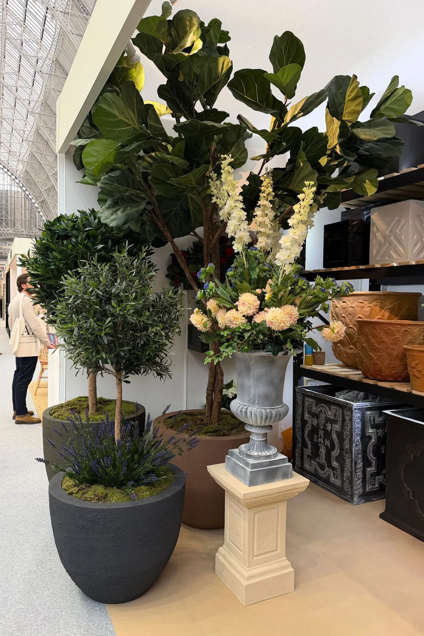 Trees and leafy plants displayed in contrasting contemporary pots and classical urns on plinths.