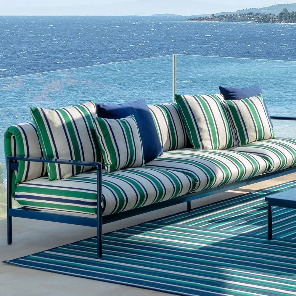 Modern outdoor sofa with blue and green striped cushions overlooking the sea
