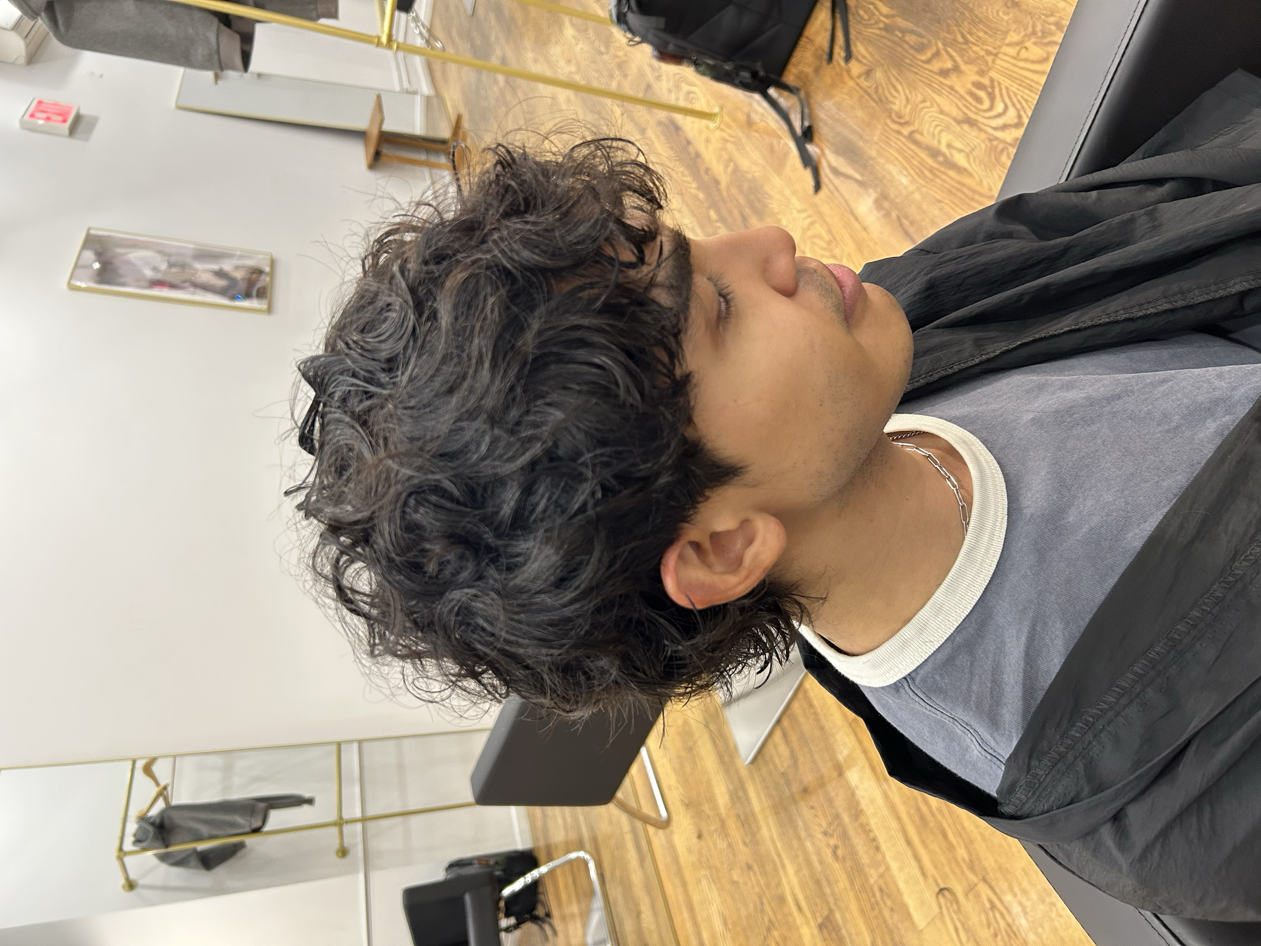 Soft men's wave perm with loose curls and natural texture on short dark hair at U&K Salon in Brooklyn.