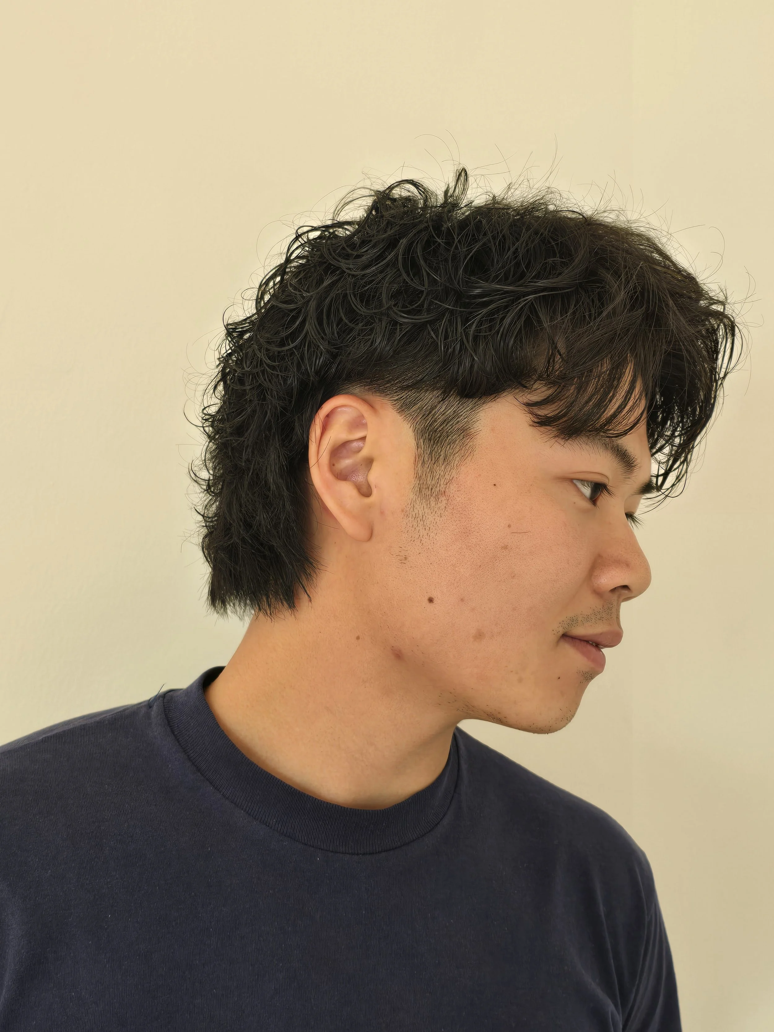 Natural-looking men's wave perm with subtle movement and textured layers on short black hair in Brooklyn.