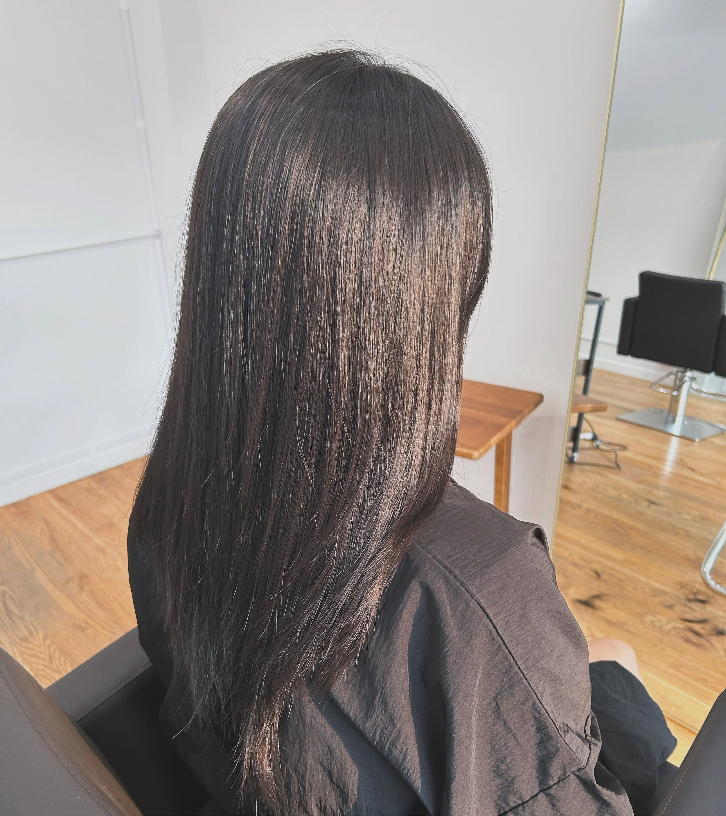 Long, glossy dark brown hair with a soft, smooth finish after HITA treatment at U&K Salon in Brooklyn.