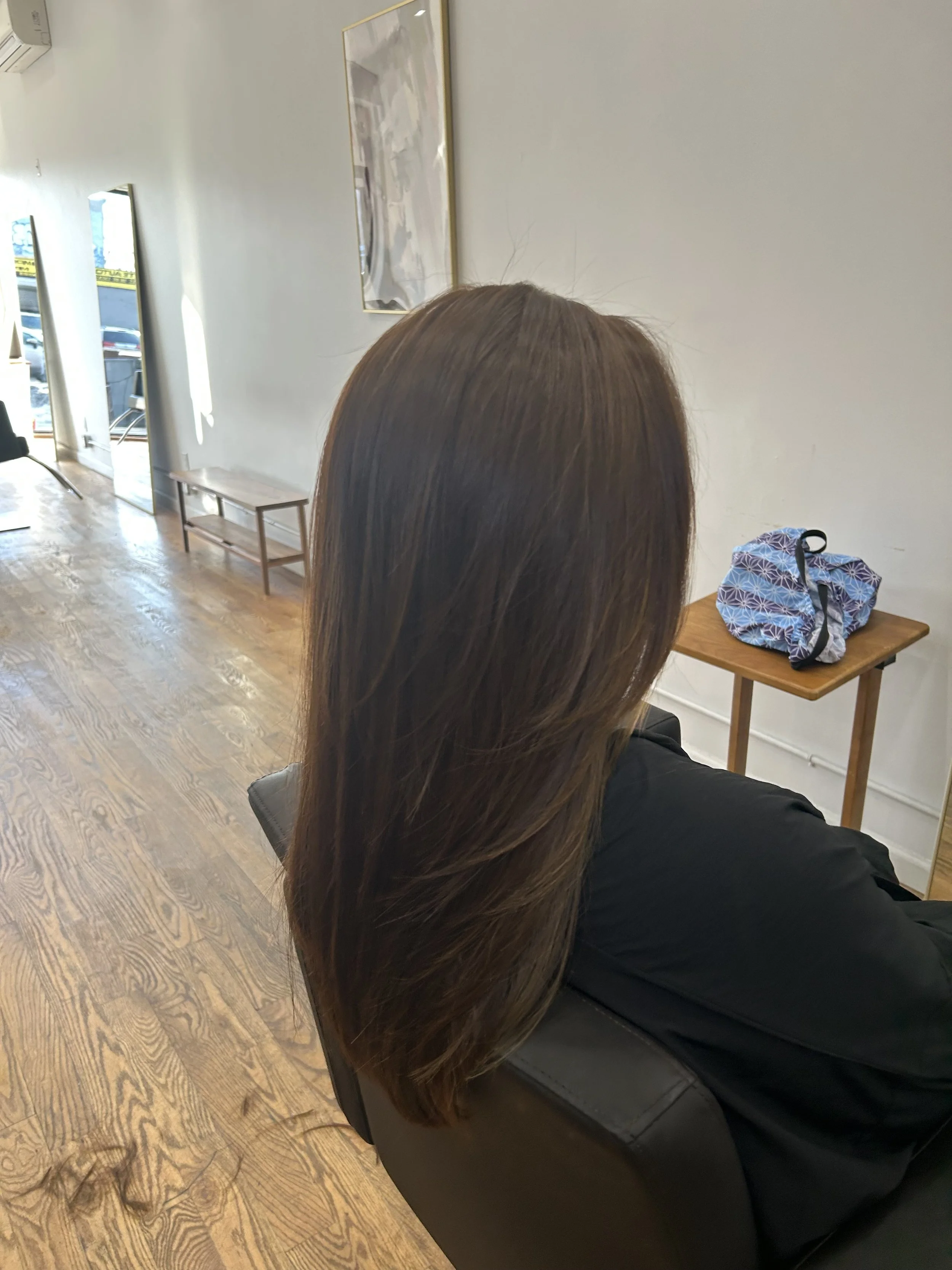 Long dark brunette hair with soft layers and a natural-looking color finish at U&K Salon in Brooklyn.