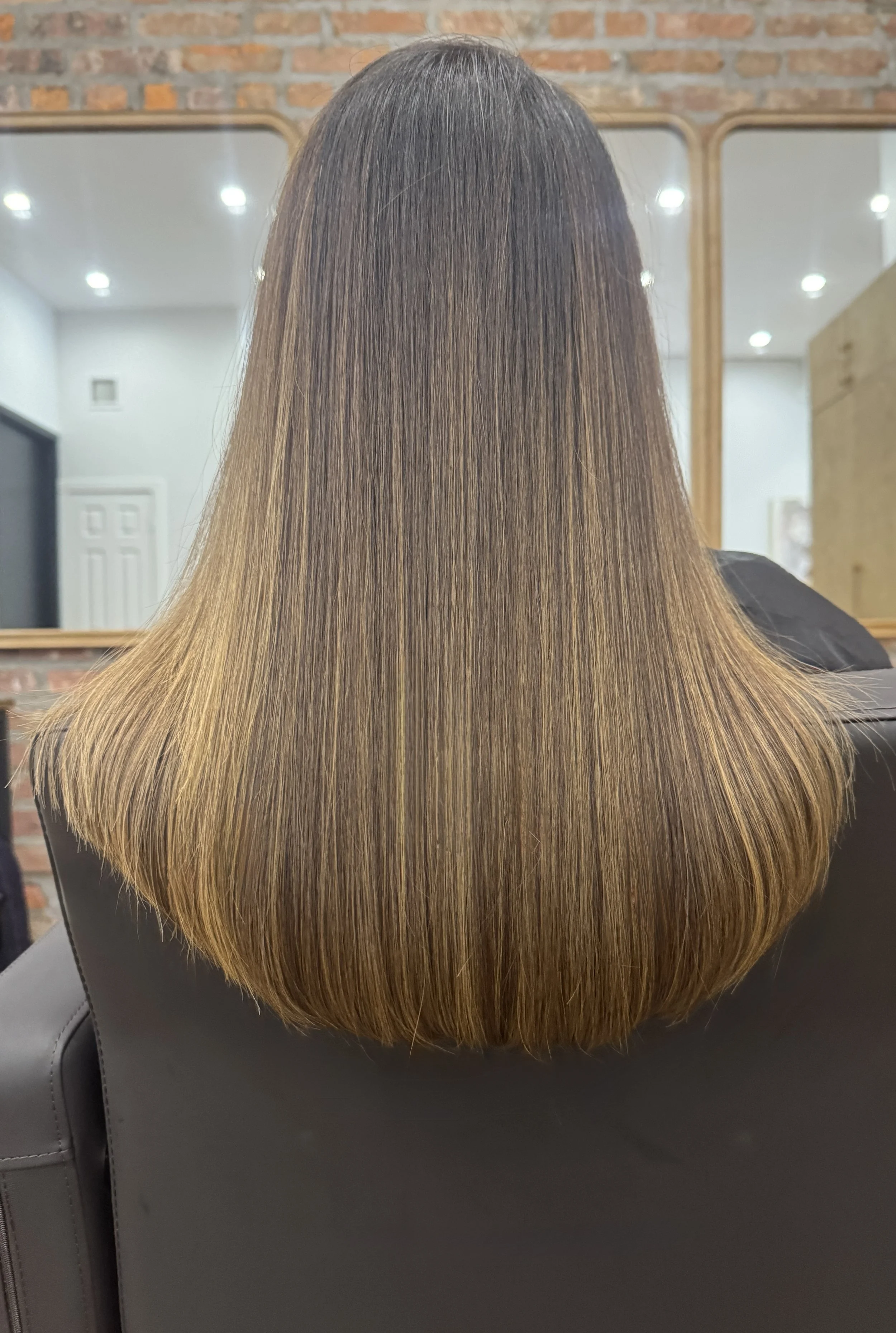 Long, smooth light brown hair with softly curved ends at U&K Salon in Brooklyn.