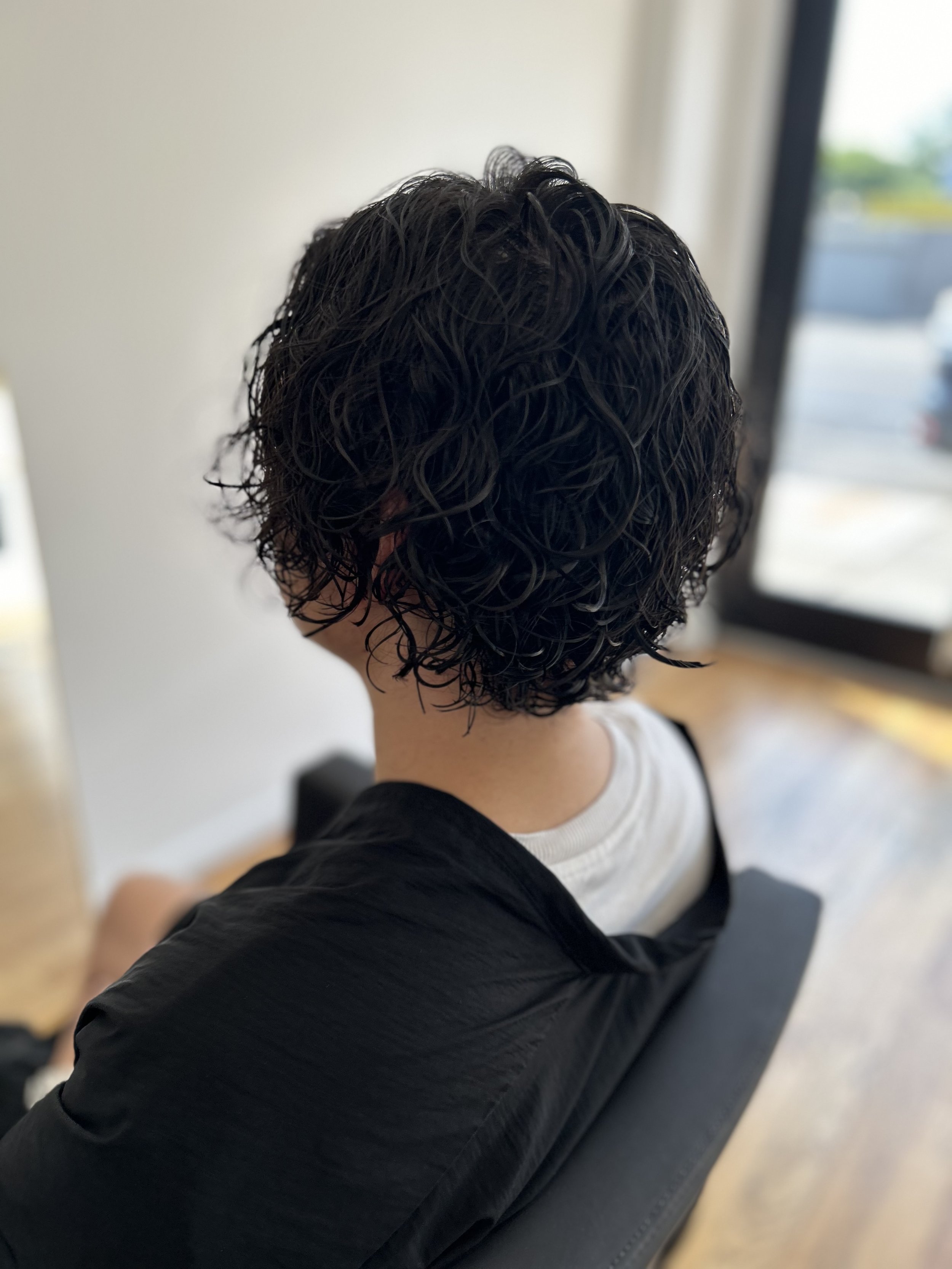 Medium-length men’s haircut with a soft perm at U&K Salon, a Japanese and Asian hair salon in Brooklyn, New York. Stylish, textured look created with expert cutting and Japanese perm techniques for all hair types.